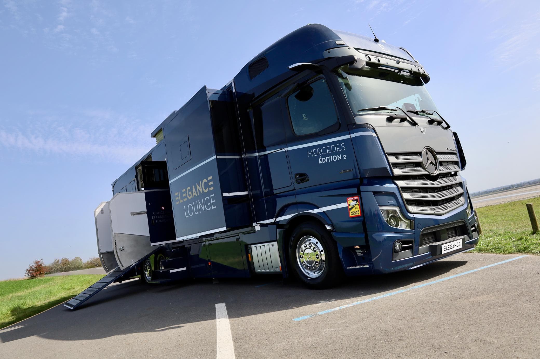 Un camión de lujo Mercedes-Benz con un lateral extendido estacionado en un día soleado.