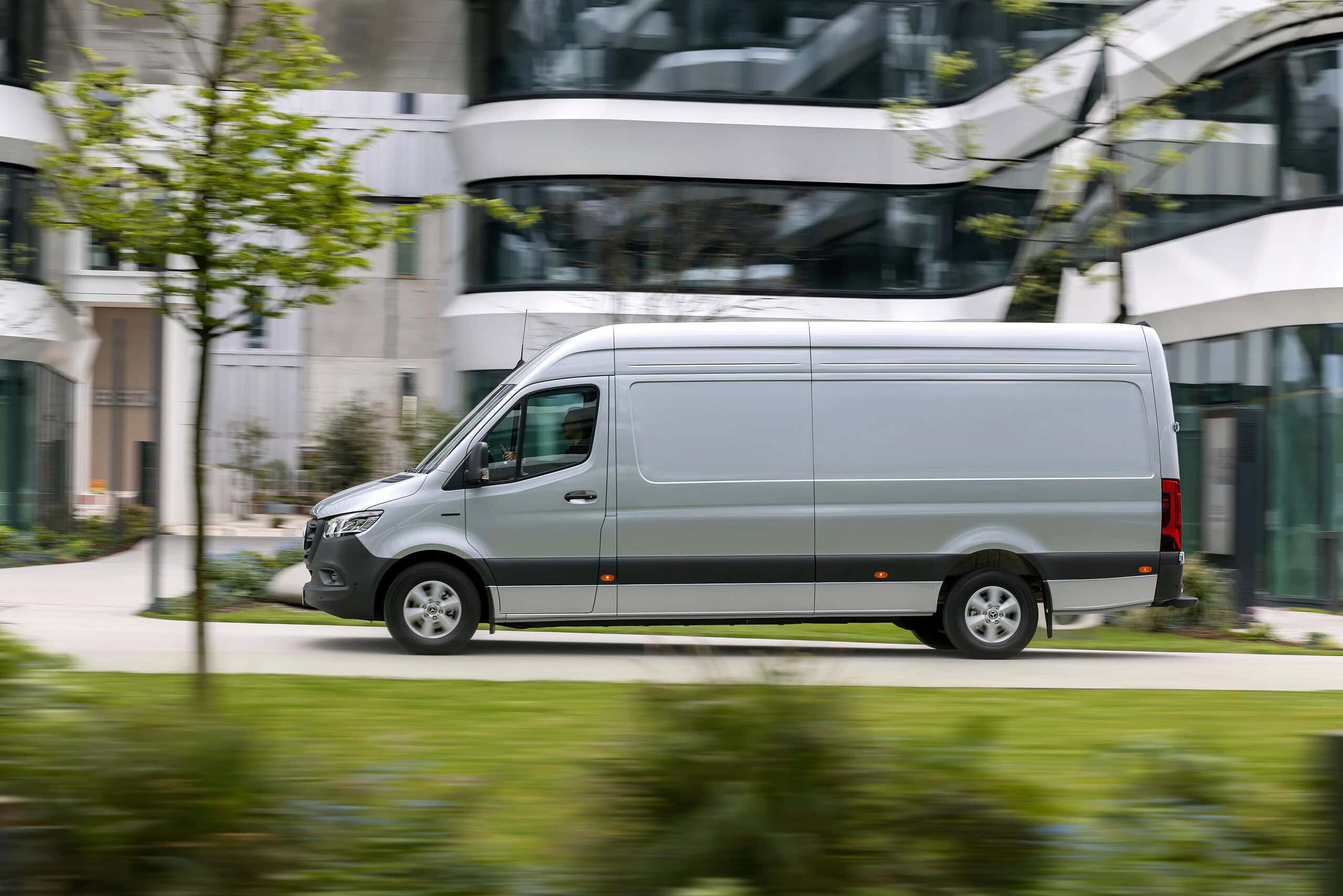 El Renault Master se desliza sin esfuerzo, una furgoneta de reparto plateada que serpentea entre edificios modernos, con una exuberante vegetación que enmarca la ecuación perfecta de la vida urbana.
