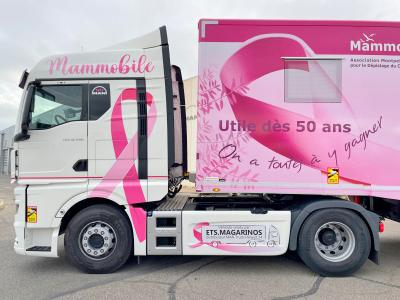 Vista lateral de un camión con cintas de concientización sobre el cáncer de mama y "MammoMobile" escrito en rosa.