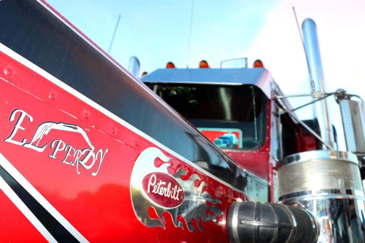 Primer plano de un camión semirremolque rojo con el logo de Peterbilt y "El Pero" pintado en el costado, detalles cromados visibles, como si hubiera sido dibujado por un borrador automático.