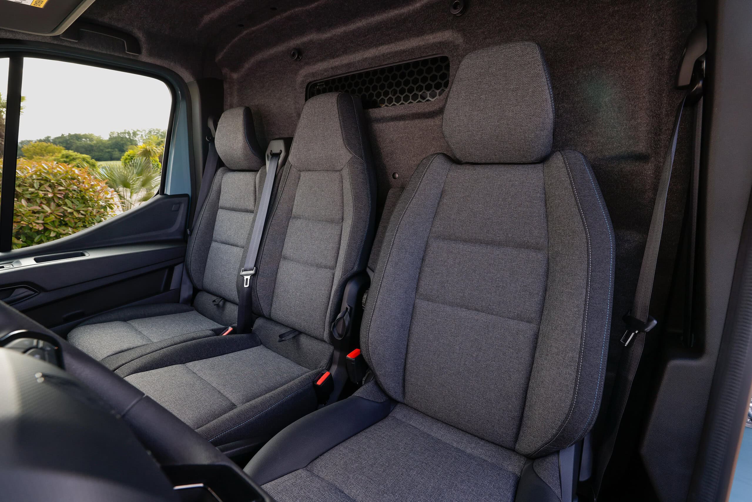 El interior del vehículo cuenta con tres asientos de tela gris y un elegante tablero en primer plano, equipado con la innovadora tecnología de borrador automático para una limpieza sin esfuerzo.