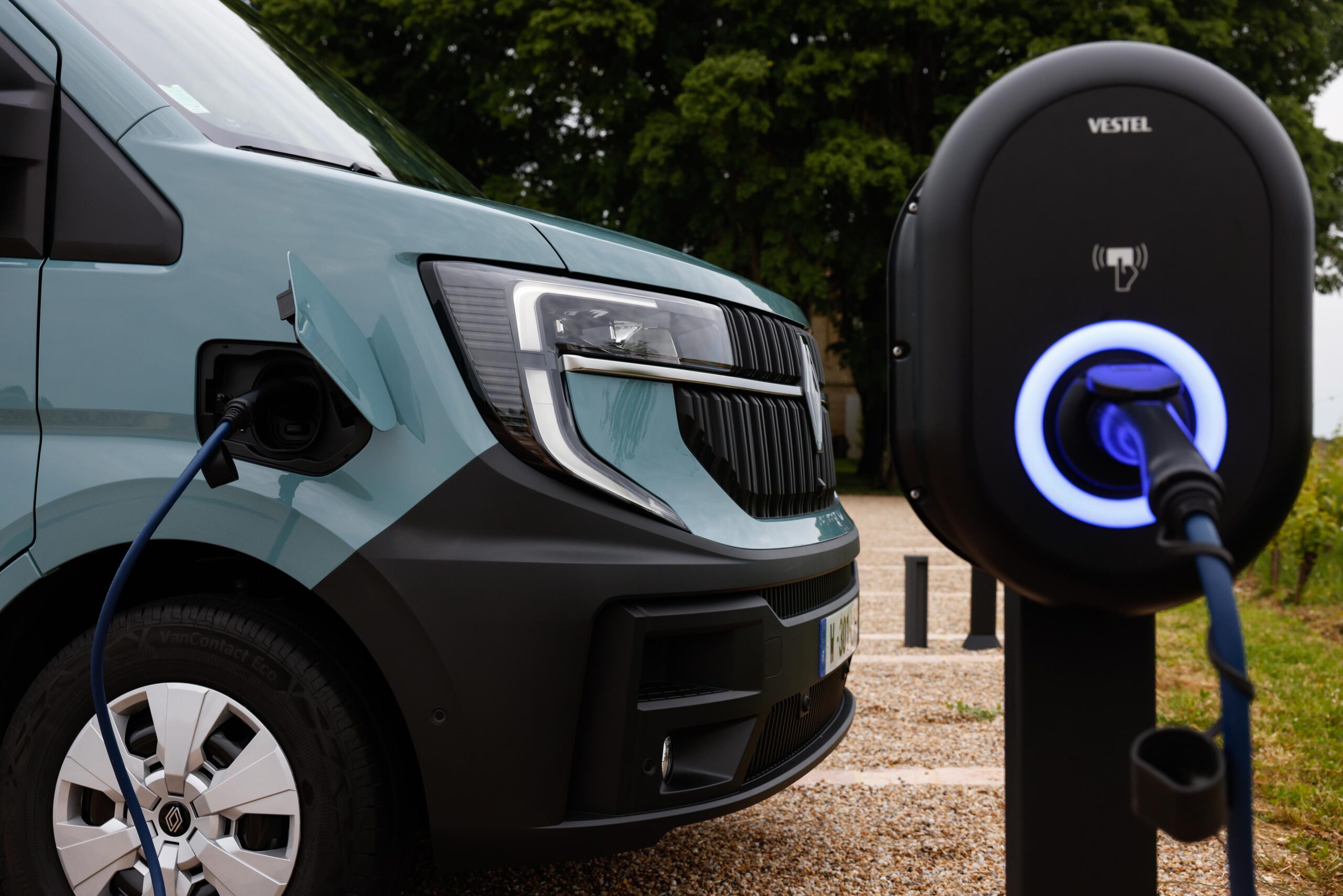 Una furgoneta eléctrica Renault Master se carga en una estación de Vestel en un frondoso entorno al aire libre, creando la ecuación perfecta de tecnología y naturaleza.