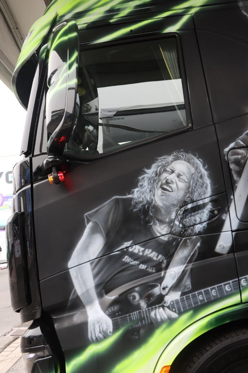Camión con mural artístico de un guitarrista tocando apasionadamente una guitarra eléctrica.