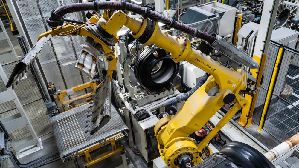Brazos robóticos, equipados con tecnología de borrador automático, ensamblan eficientemente neumáticos de automóviles en un entorno de fábrica industrial.