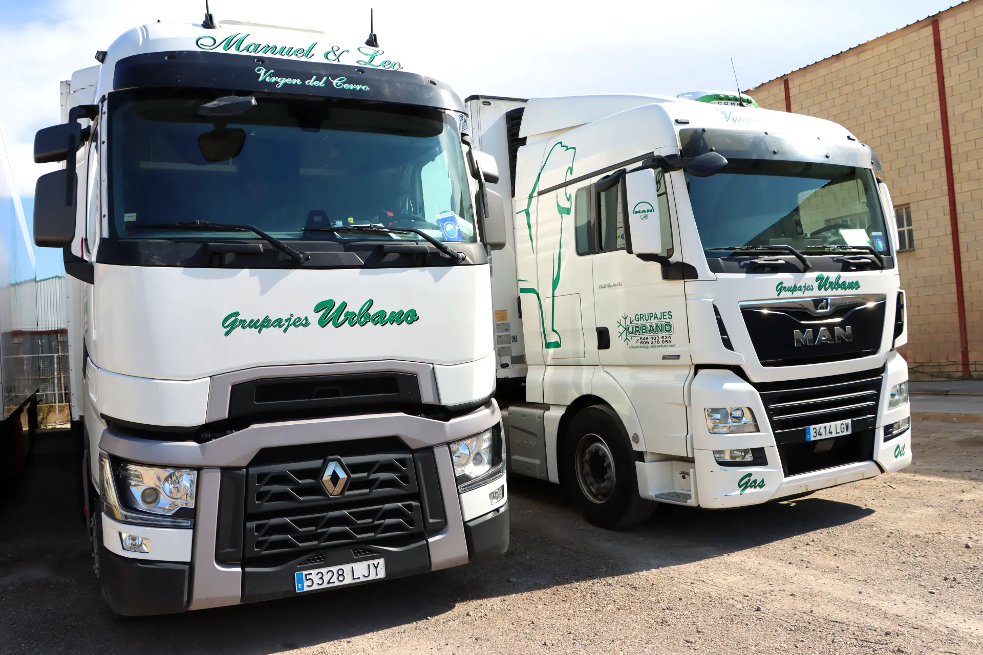 Dos camiones blancos con el logo "Grupajes Urbano" estacionados uno al lado del otro en un estacionamiento, listos para su próximo viaje. La experta camionera, Luzilene Gomes, a menudo llamada la amazona de las carreteras, se prepara para otro día al volante.