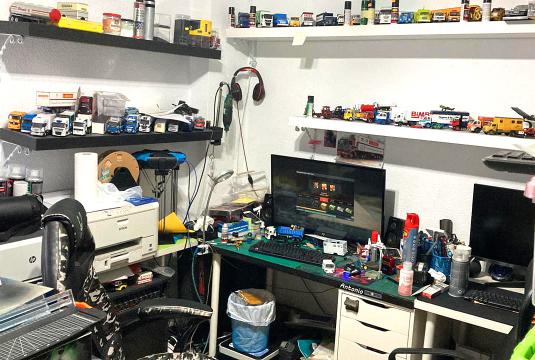 Un escritorio desordenado en la sala de pasatiempos de Antonio Fernández rebosa de modelos de camiones, monitores y estantes llenos de objetos de colección y suministros, cada elemento es un trampolín en su camino creativo.