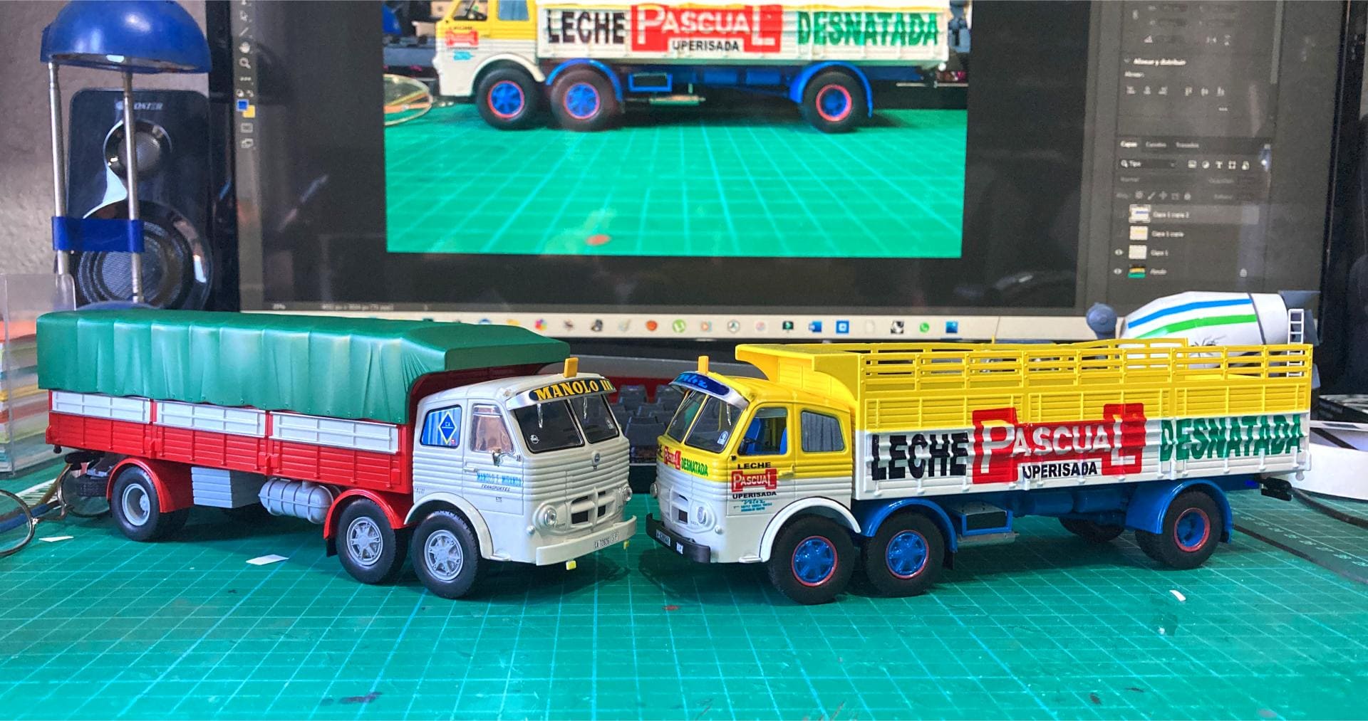 Sobre un escritorio, dos maquetas de camiones se mantienen firmes, captadas perfectamente en un monitor detrás de ellos. Es casi como si estuvieran listos para enfrentar cualquier obstáculo en el camino que tienen por delante, recordando una obra de arte de Antonio Fernández.