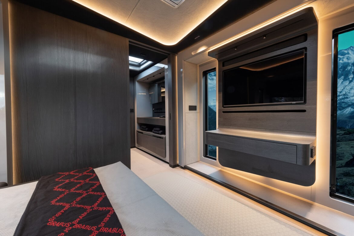 Experimente el lujoso interior de la autocaravana Brabus, que cuenta con iluminación ambiental, un televisor grande y una cómoda cama. El diseño Big Boy 1200 garantiza la comodidad, mientras que una ventana panorámica le permite disfrutar de impresionantes vistas a las montañas.