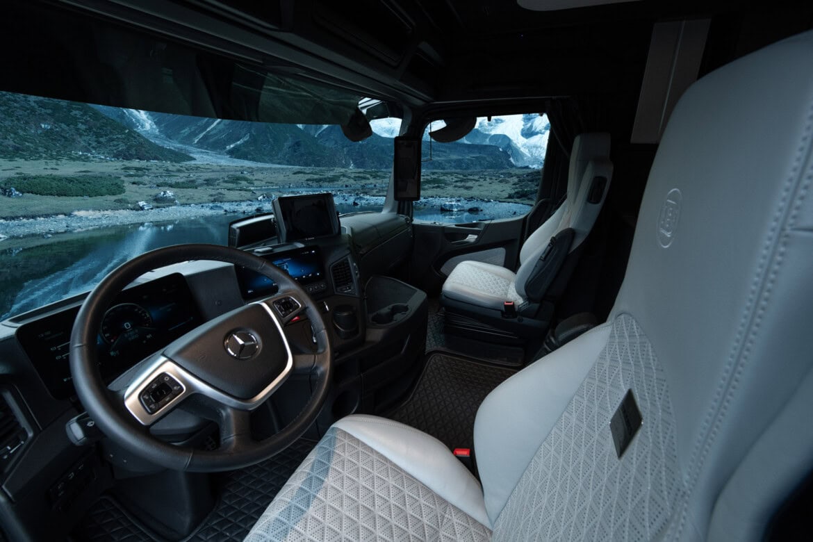 El interior de la cabina se siente tan espacioso como una autocaravana, con dos lujosos asientos y grandes ventanas que enmarcan un pintoresco paisaje montañoso exterior.