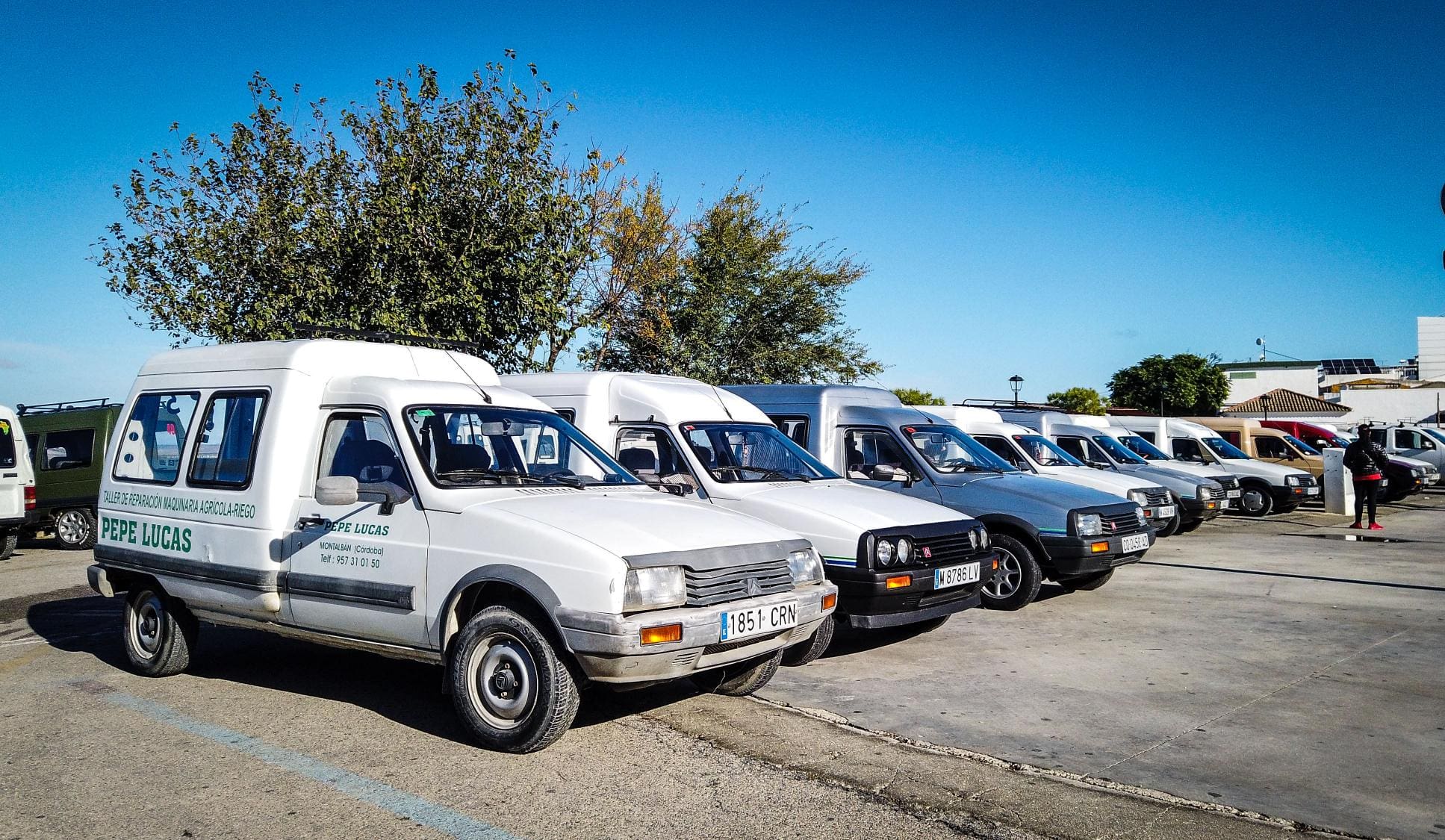 Una fila de furgonetas Citroën C-15 blancas estacionadas en un estacionamiento en un día claro, listas para la próxima expedición Camper-15.
