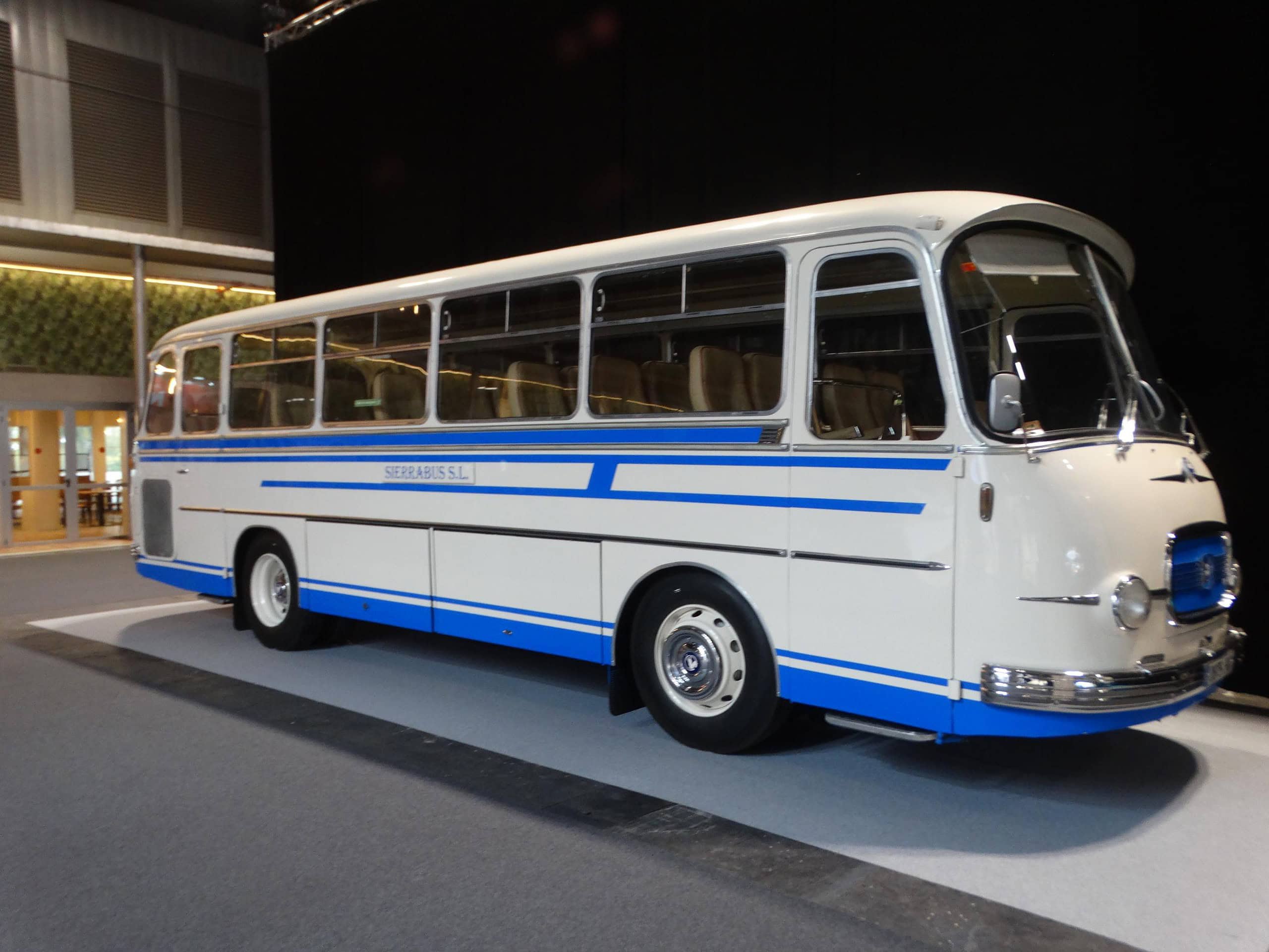 Un Autobús y Autocar antiguo blanco y azul con grandes ventanales se exhibe en el interior, captando la atención en la Feria Internacional del Autobús y del Autocar y contribuyendo al crecimiento de visitantes.