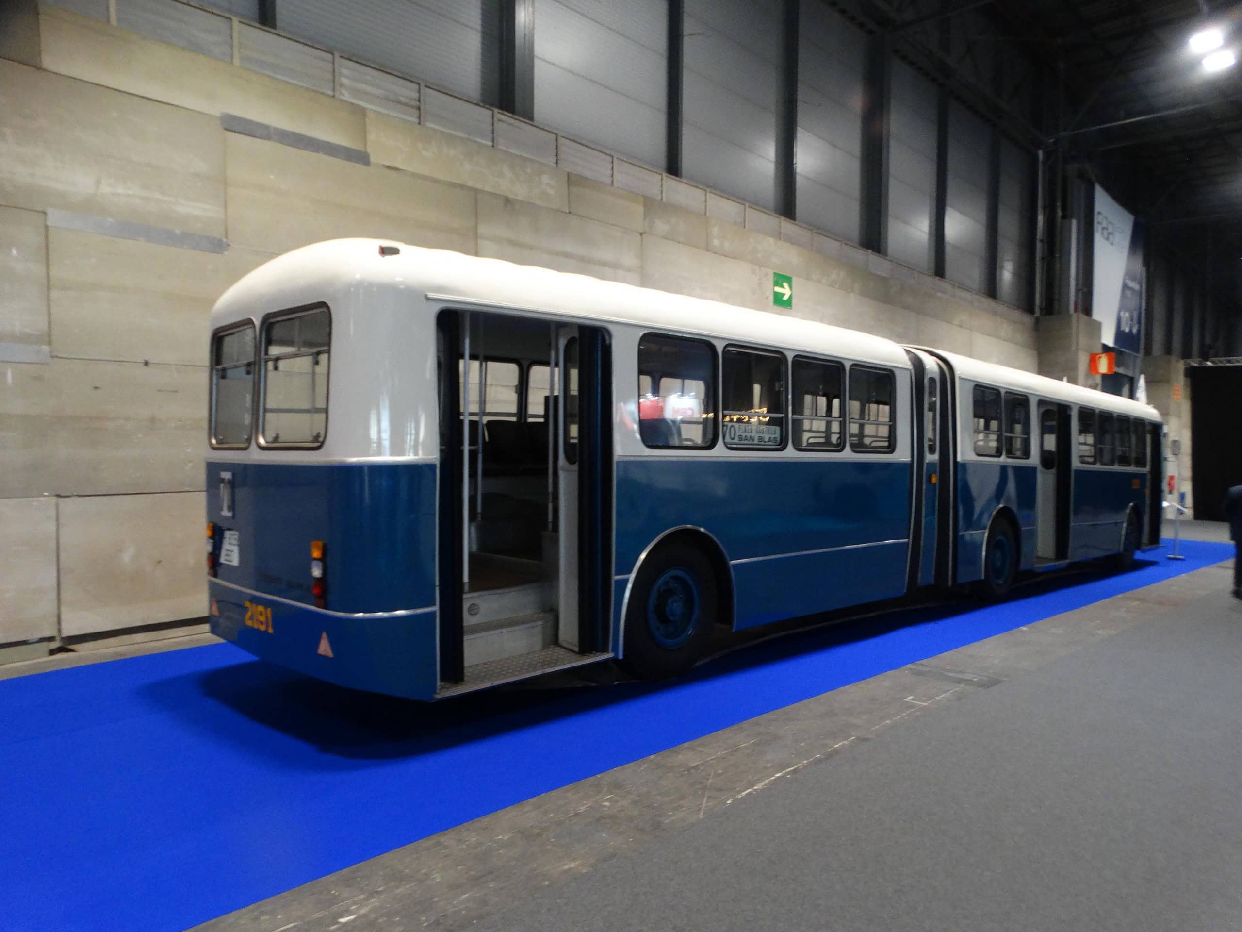 El autobús articulado vintage azul y blanco se exhibe con orgullo en el interior, sobre una llamativa alfombra azul, en la Feria Internacional de Autobús, donde cautiva a los visitantes con su encanto atemporal.