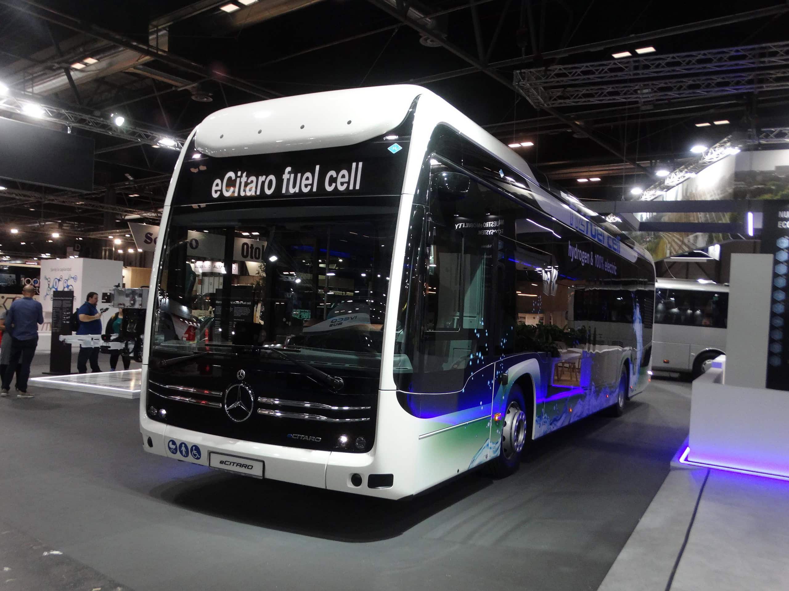 Un elegante autobús blanco Mercedes-Benz eCitaro de pila de combustible se exhibe en el interior de la Feria Internacional del Autobús y del Autocar, atrayendo crecimiento de visitantes con su diseño innovador y tecnología ecológica.