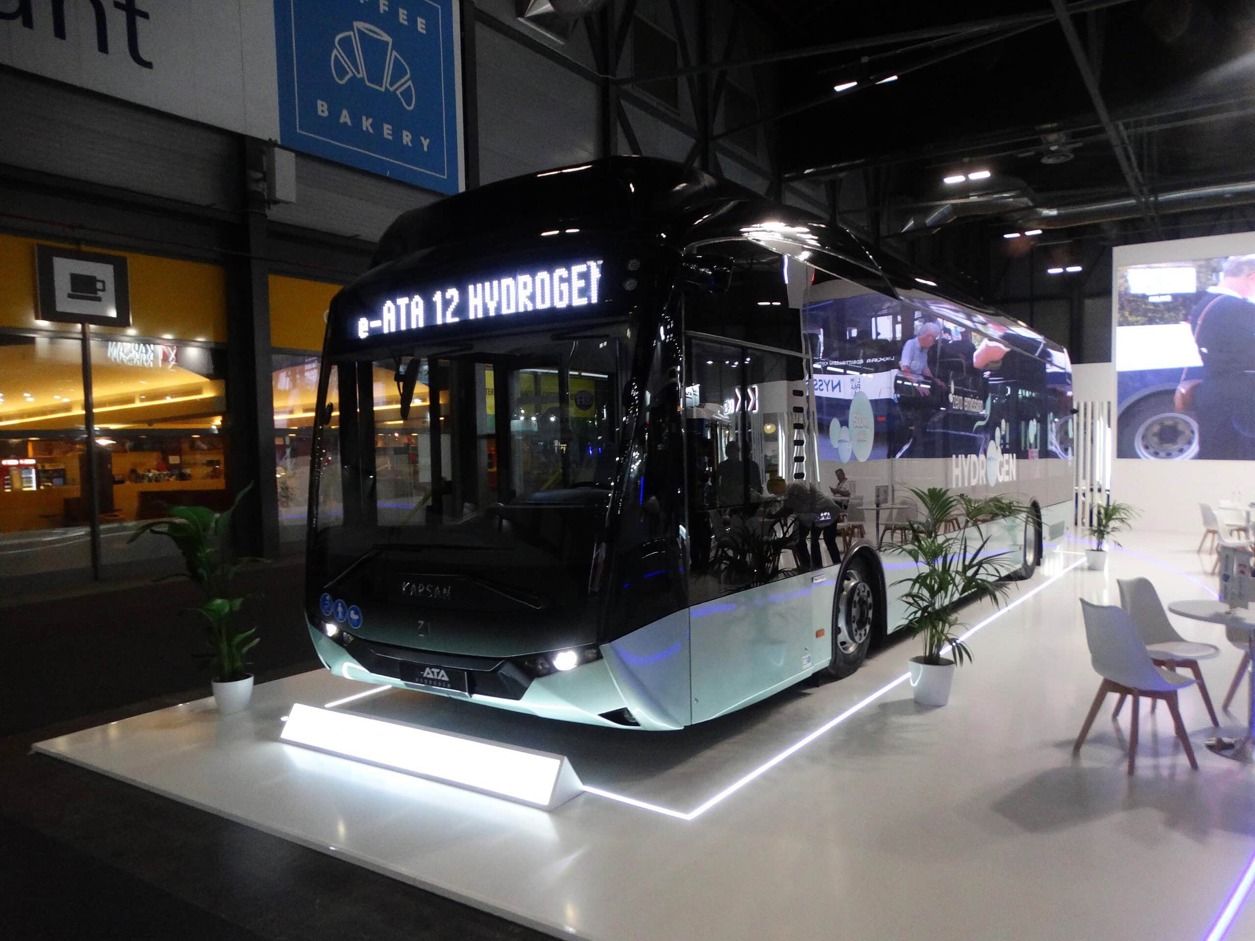 Un elegante y moderno autobús propulsado por hidrógeno se exhibe en el interior, en medio de una iluminación brillante y una exuberante vegetación, en la Feria Internacional Autobús, atrayendo cada vez más visitantes.
