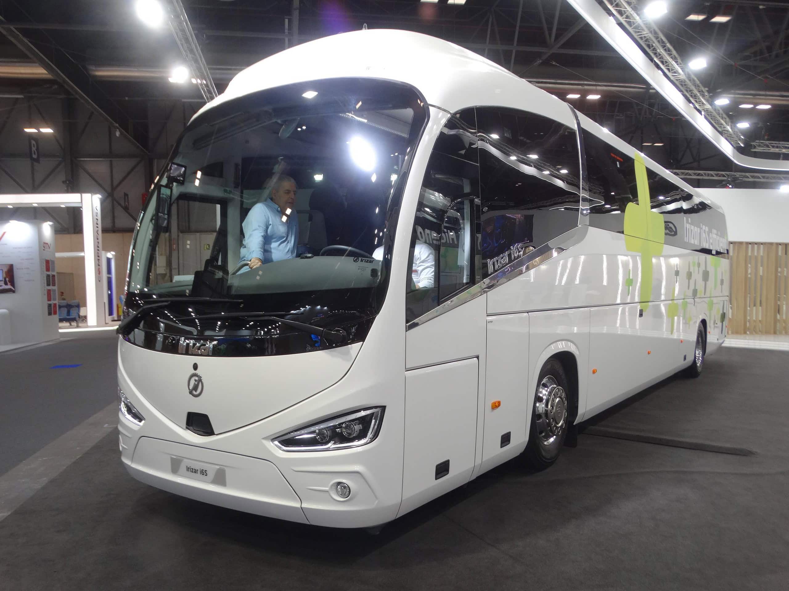 Un elegante autobús de lujo Autocar de color blanco se exhibe en la Feria Internacional del Autobús, mientras visitantes curiosos exploran su moderno interior.
