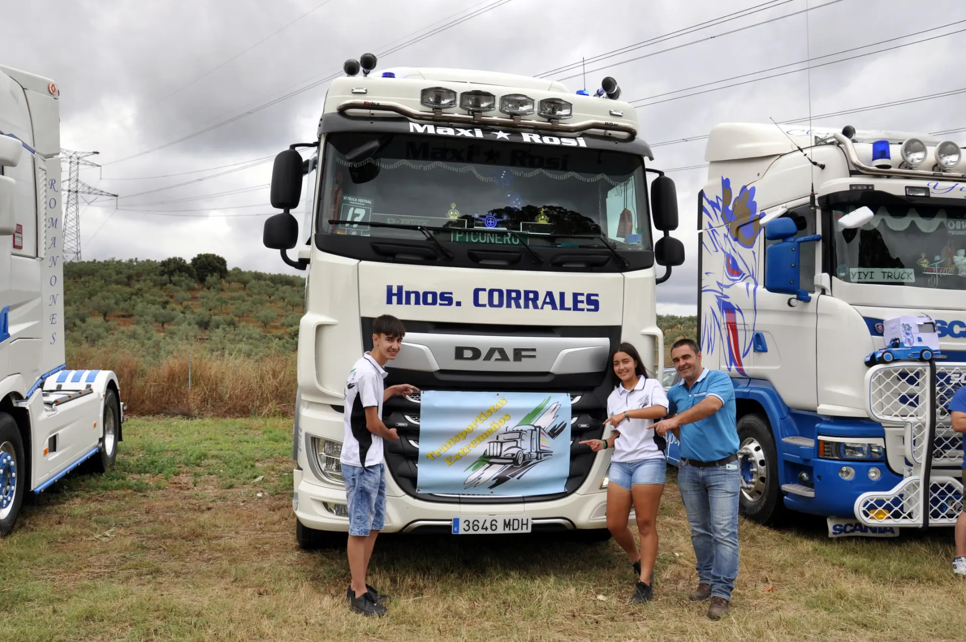 Tres personas posan frente a un camión blanco, sosteniendo orgullosamente una pancarta decorativa como si se tratara de un "Borrador automático" dispuesto a trazar infinitas posibilidades.