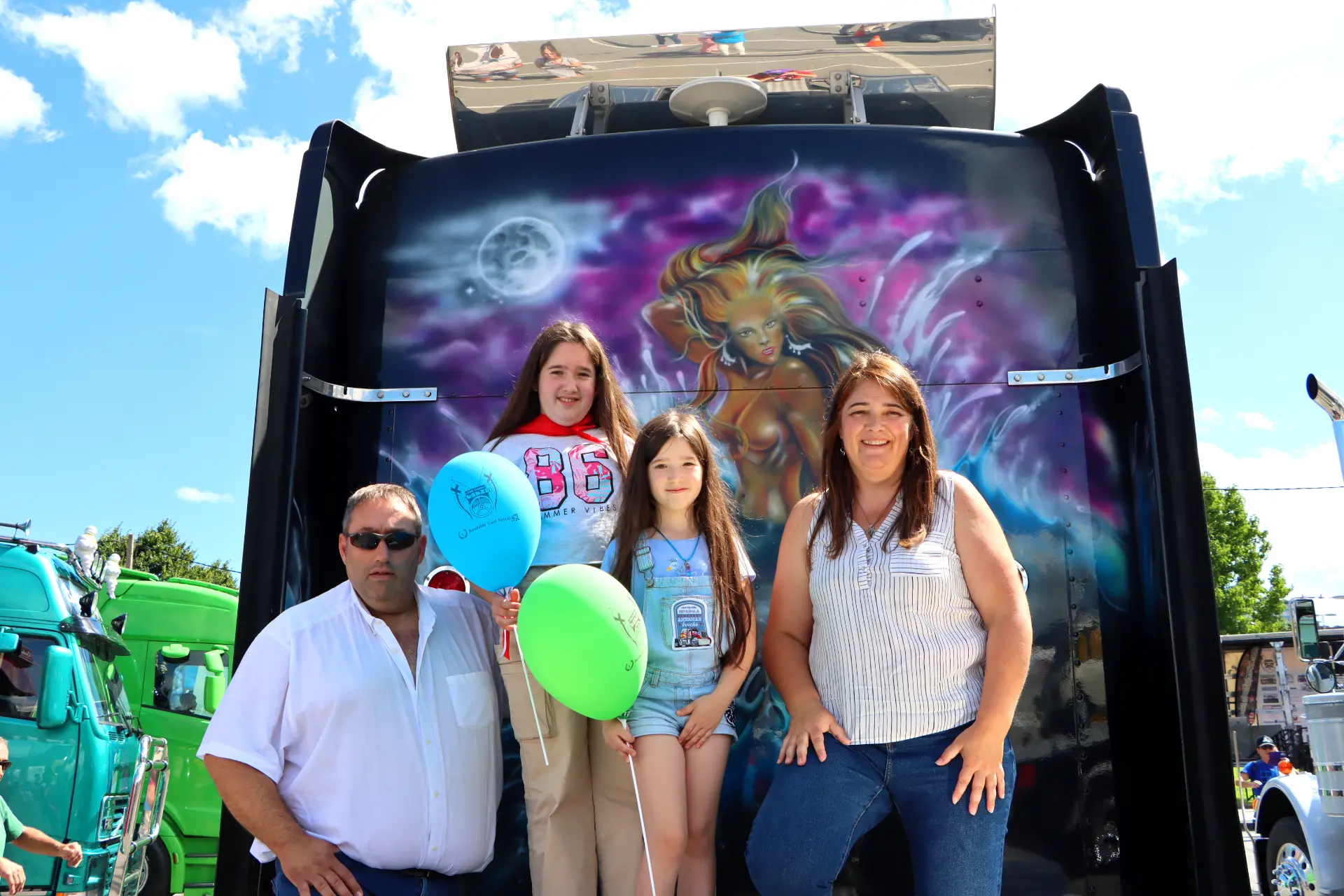 Familia posando delante de un camión pintado con globos en el Festival de Camiones de Barakaldo, disfrutando de un día soleado.