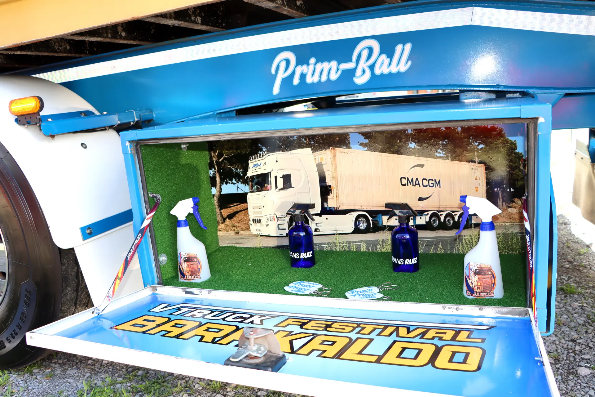 Decoración de camión con sprays de limpieza, maqueta de camión y cartel de “Barakaldo Truck Festival” dentro de un compartimento azul, capturando a la perfección lo que nos une en este vibrante evento.