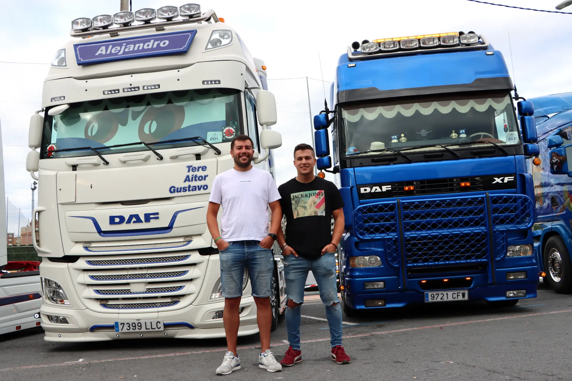 Dos hombres se sitúan delante de dos grandes camiones DAF, uno blanco y otro azul, aparcados uno al lado del otro en el Festival de Camiones de Barakaldo.