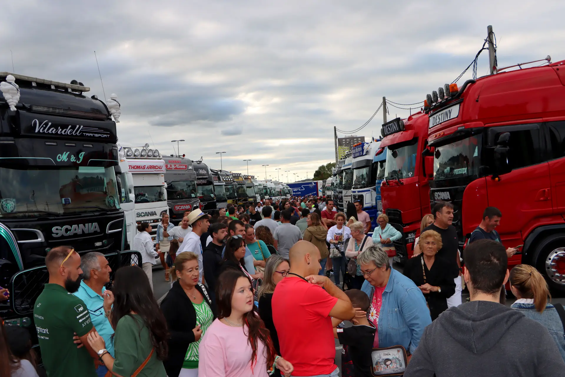 Una gran multitud se reúne entre camiones aparcados bajo un cielo nublado en el V Festival de Camiones de Barakaldo, celebrando el espíritu de "lo que nos une nos reúne".