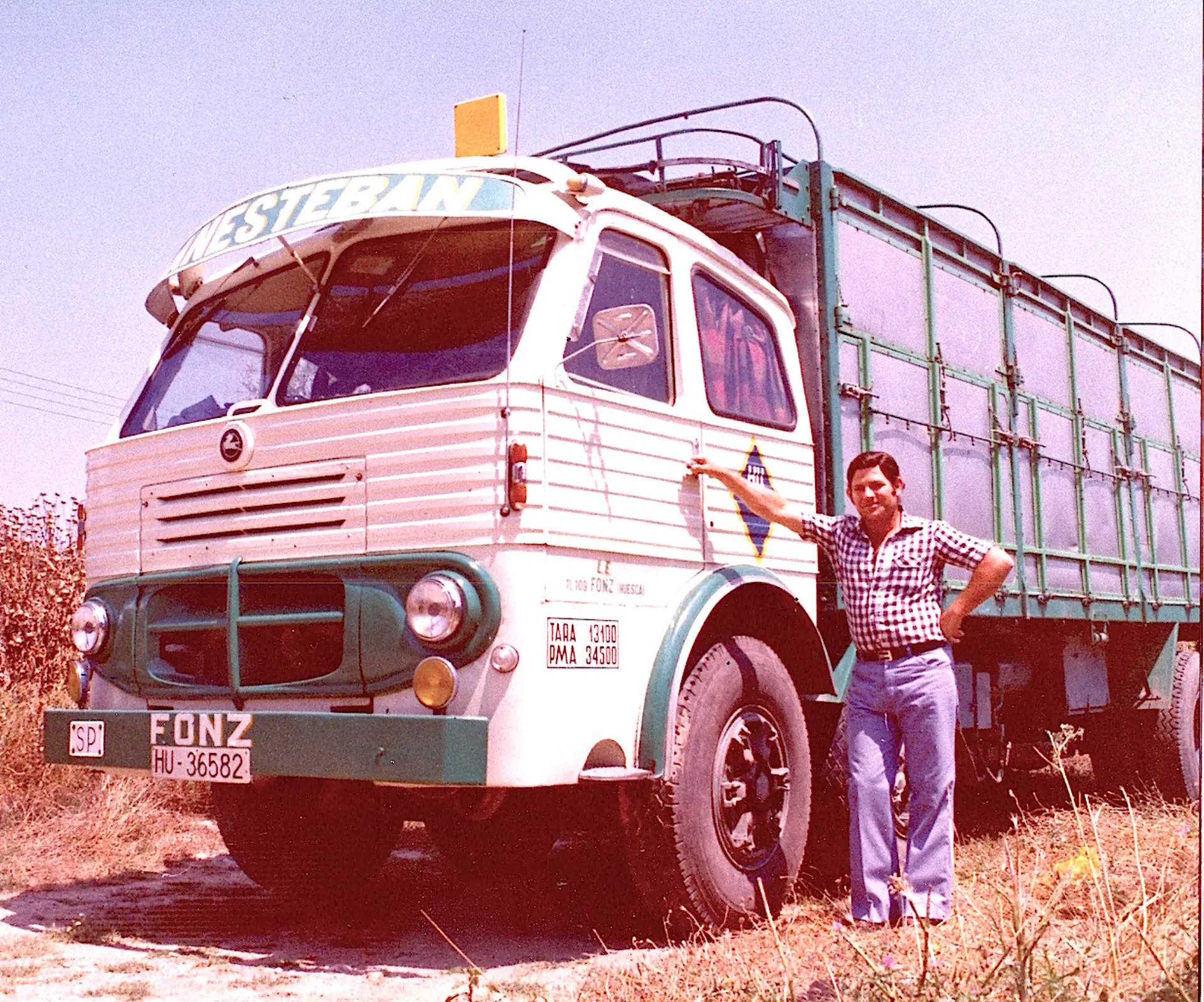 Un hombre se encuentra orgulloso junto a un camión antiguo verde y blanco llamado "Esteban" en un día soleado en Sevilla, donde Antonio Plata se ha hecho famoso por su colección de vehículos clásicos, que incluye bellezas como esta.