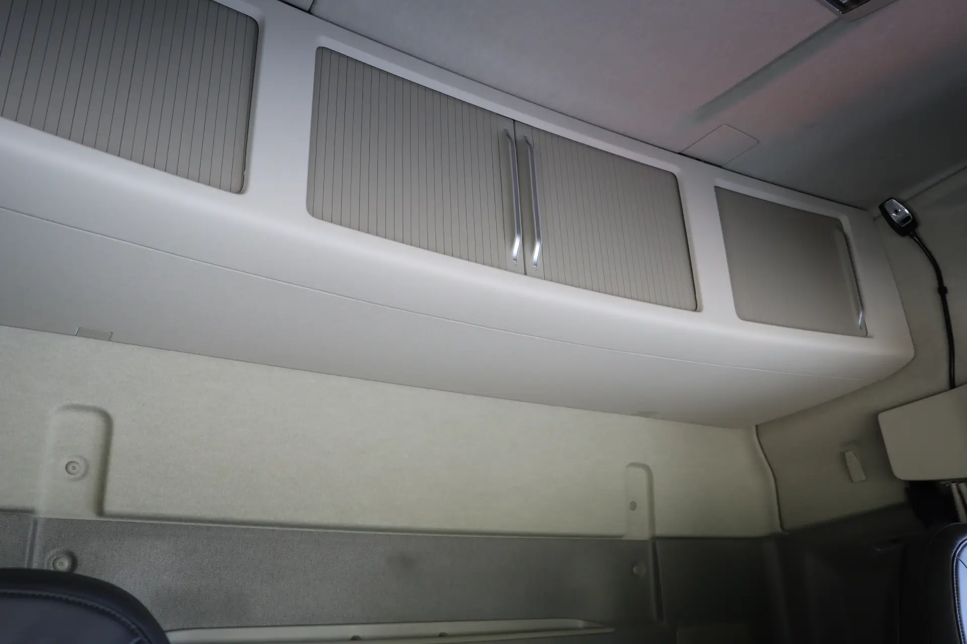 Vista interior de la cabina de un camión Volvo FH, completa con compartimentos de almacenamiento superiores cerrados y una única luz exterior, optimizada con la función I-Save para una mayor eficiencia.
