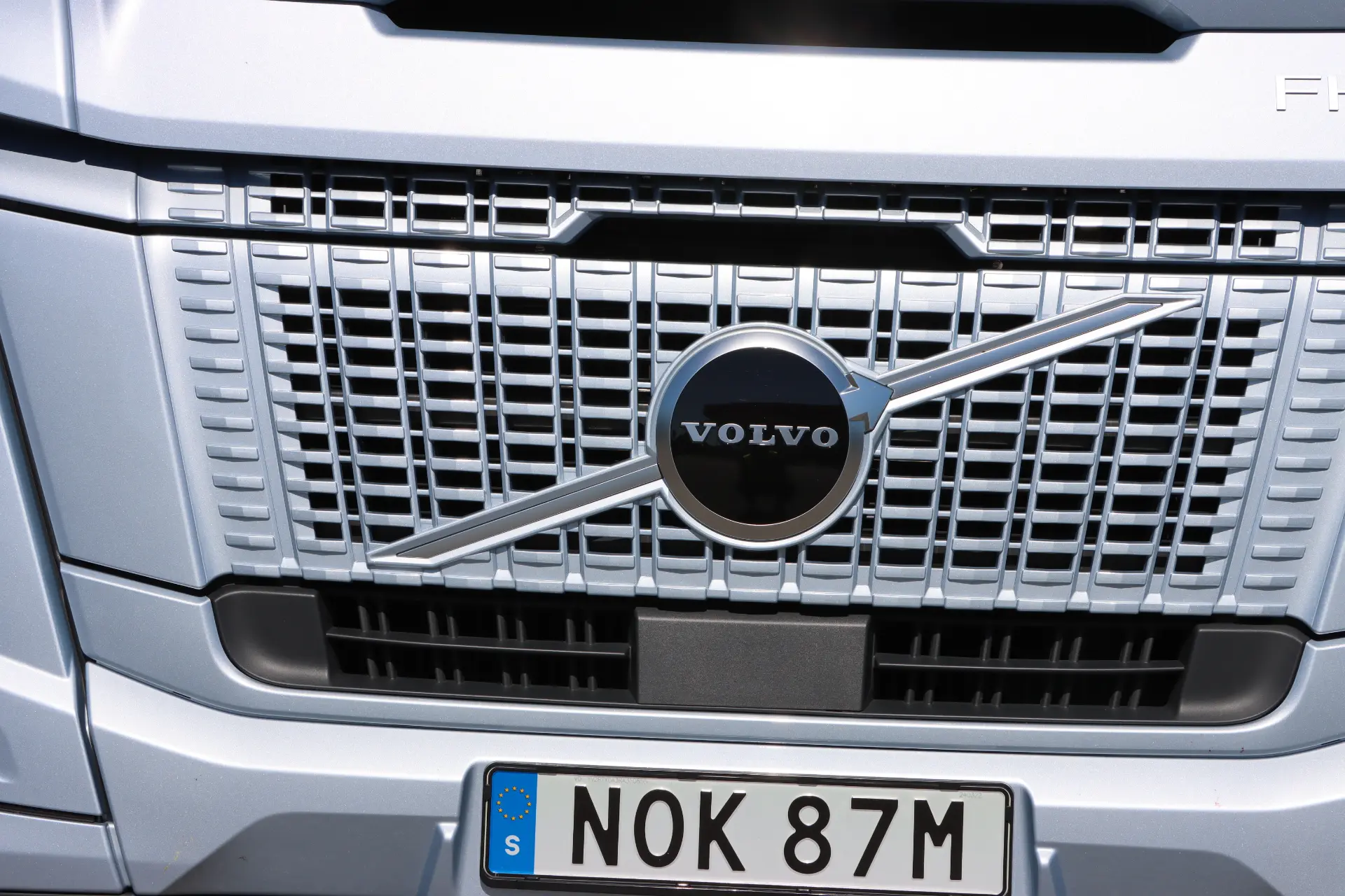 Primer plano de la parrilla del camión Volvo FH Aero 460, que muestra el logotipo y la matrícula icónicos. Probamos su avanzada tecnología I-Save para una mayor eficiencia.