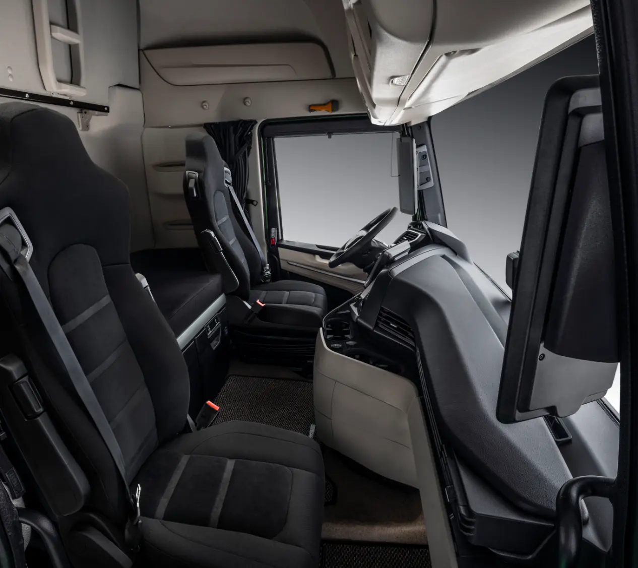 El interior de la cabina del camión Iveco MY24 cuenta con dos elegantes asientos negros, un tablero moderno y un volante, todos diseñados para una comodidad y eficiencia óptimas.