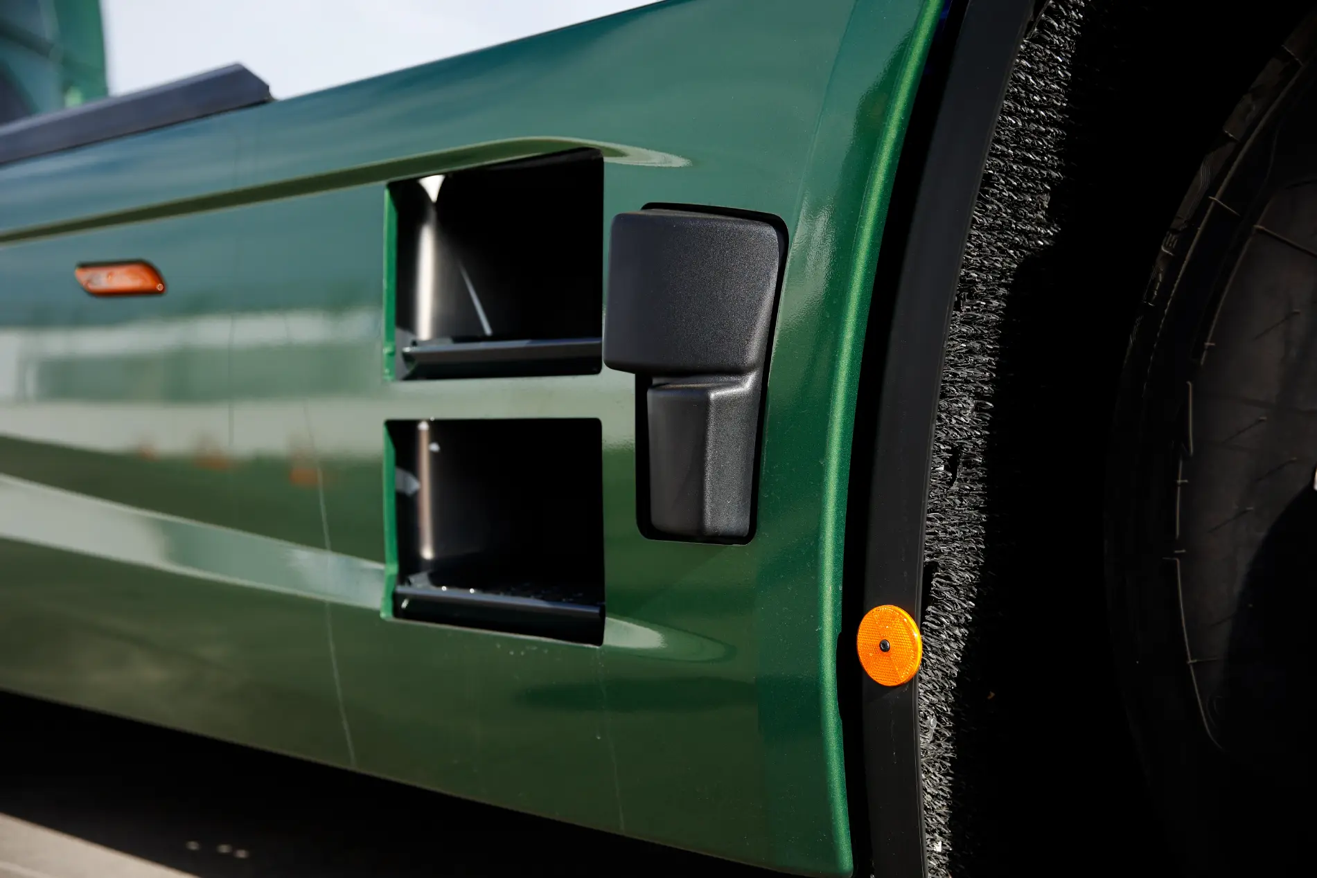 Primer plano del lateral de un vehículo Iveco verde, que muestra las salidas de aire y un neumático con un distintivo reflector naranja, que ofrece una pista de las características avanzadas de la gama MY24.