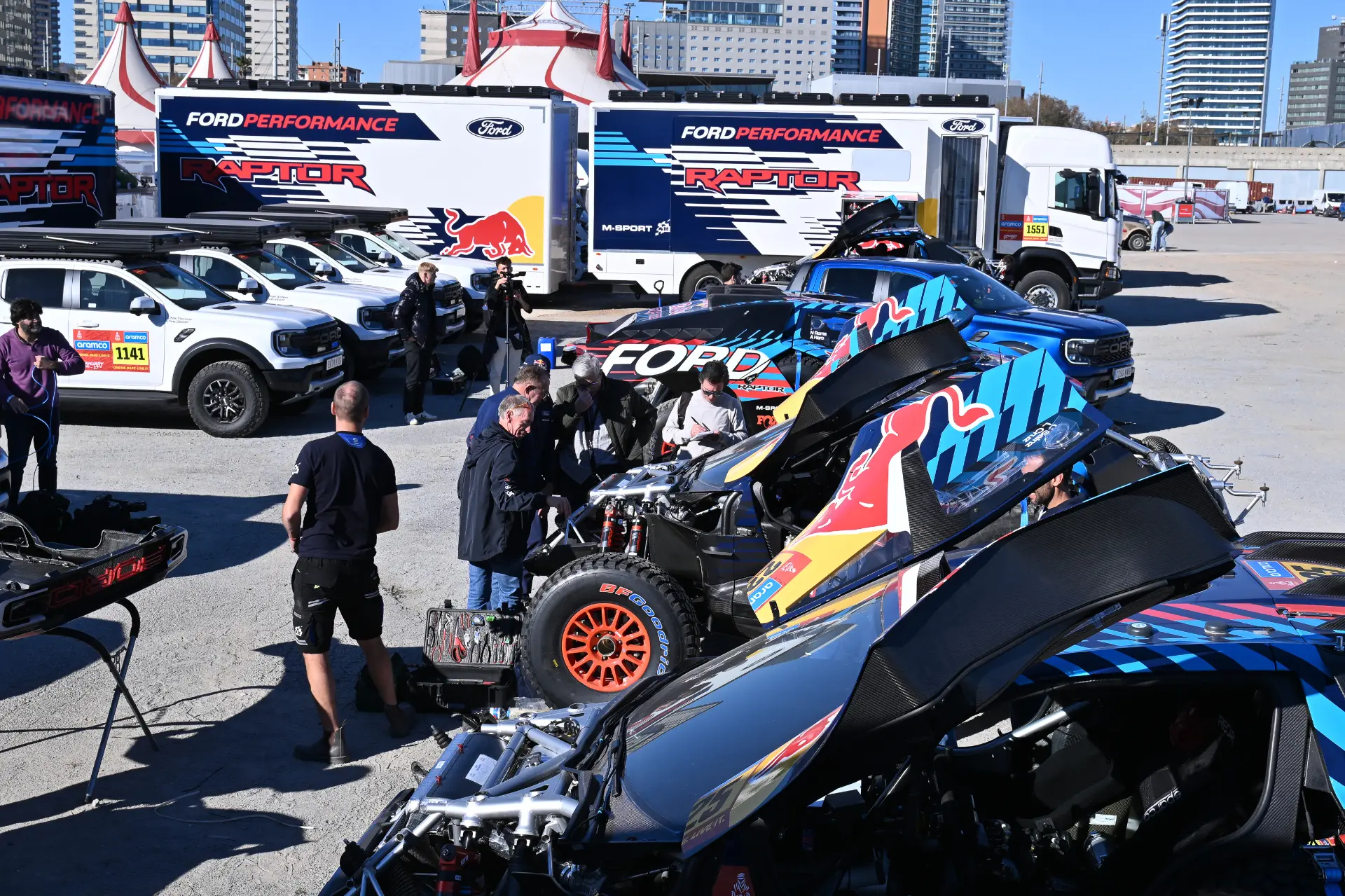Los mecánicos no paran de poner a punto en el aparcamiento coches y camiones de carreras, adornados con los logos de Ford y Red Bull. Entre ellos destaca el Ford Raptor T1+, que se prepara para el Dakar 2025, una cita que promete emociones a toda velocidad en un escenario que recuerda a las legendarias carreras de Carlos Sainz.