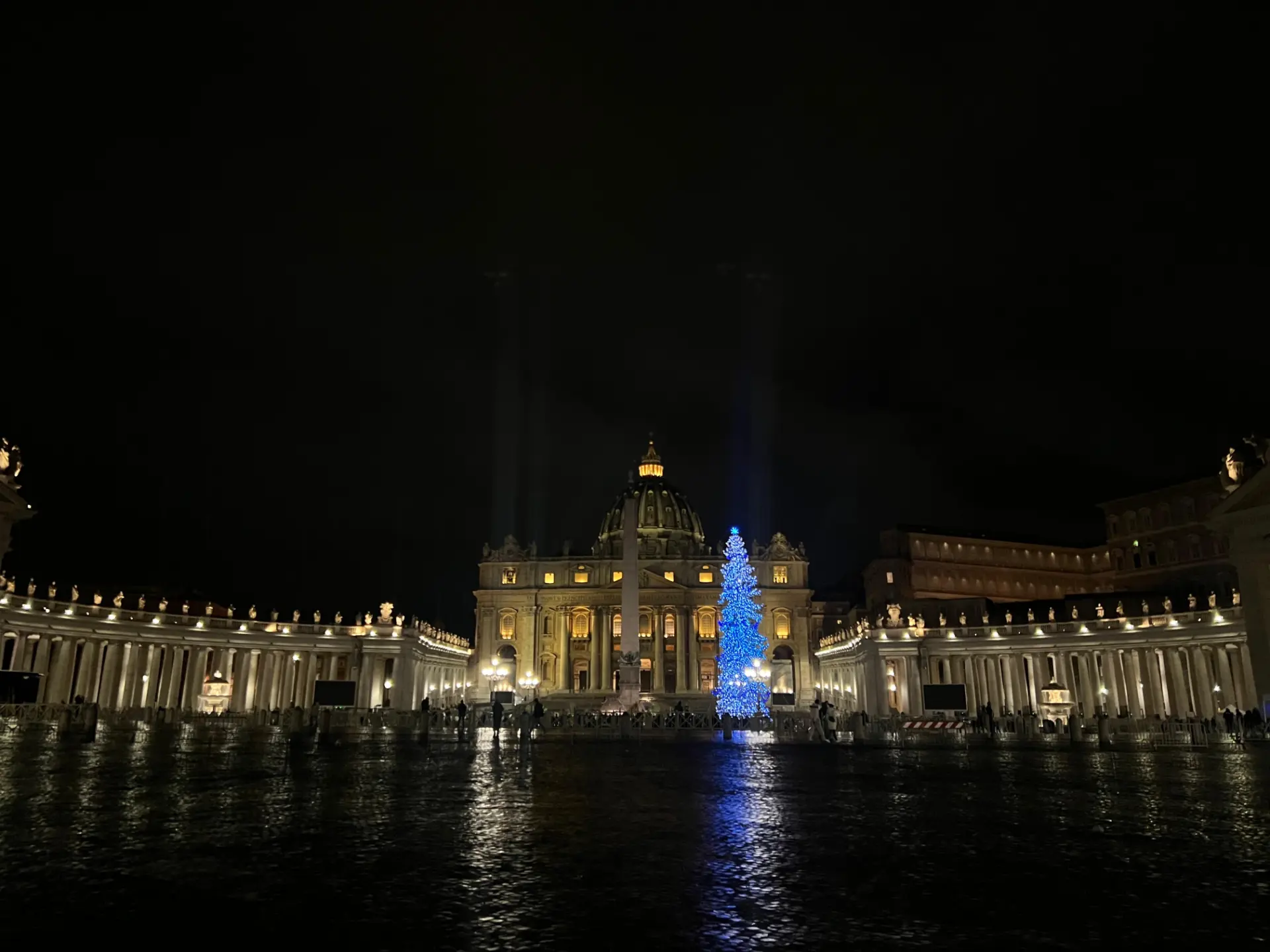 La Basílica de San Pedro iluminada por la noche con un árbol de Navidad azul brillante en la Ciudad del Vaticano, que proyecta un brillo mágico que recuerda a una pintura automática que cobra vida.