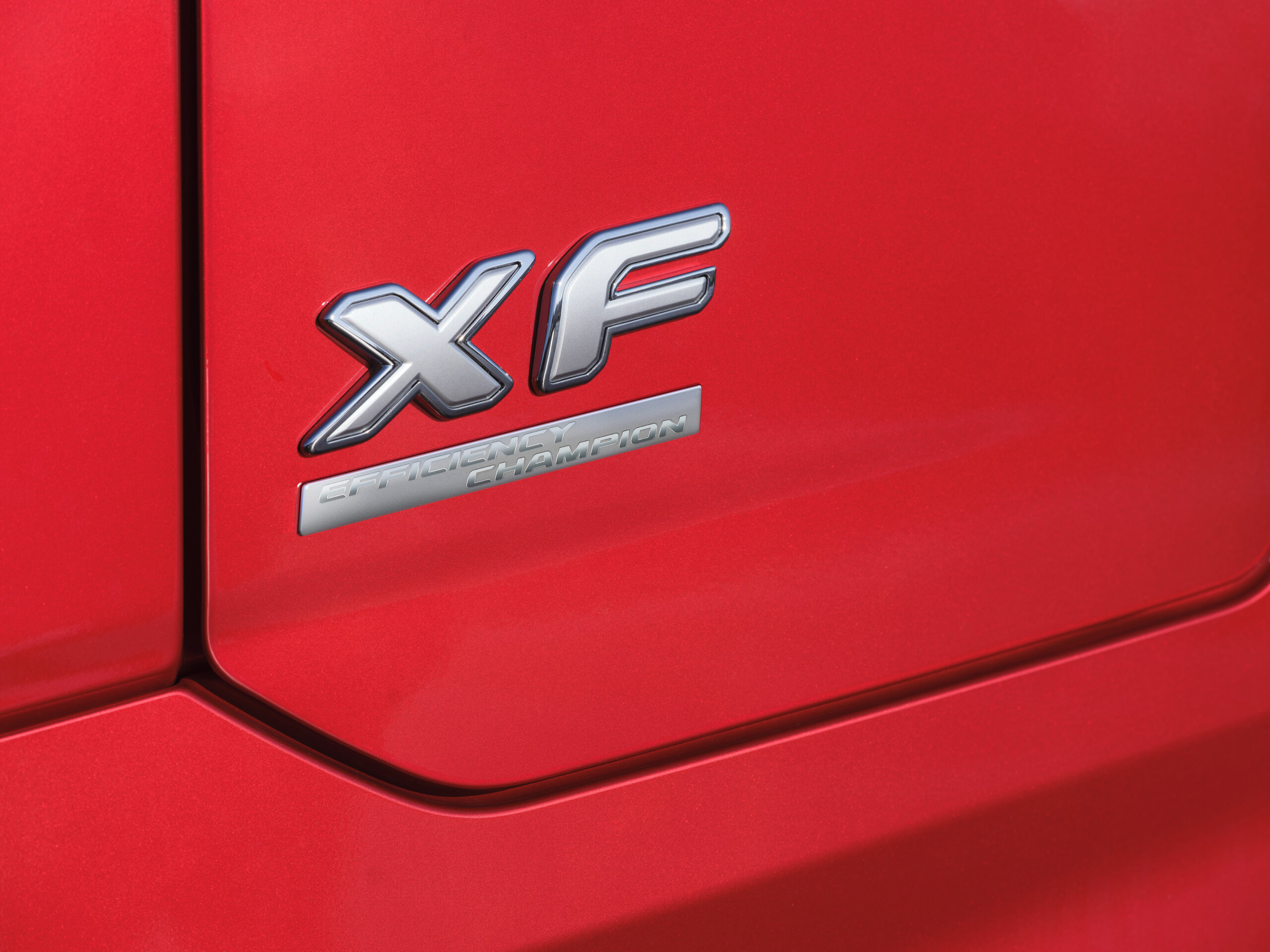 Primer plano de un automóvil rojo que lleva las insignias "XF" y "Champion" en su costado, lo que hace alusión a su herencia de borrador automático.