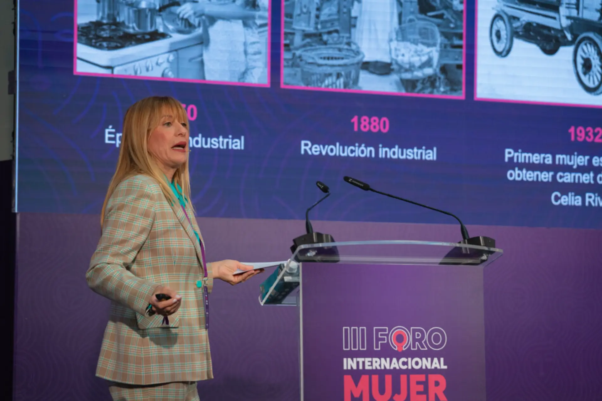 Una mujer se yergue con confianza en el podio y ofrece una presentación convincente sobre hitos históricos en los logros de las mujeres. Sus opiniones resuenan con historias de figuras pioneras que han dado forma a sectores como el del transporte, donde las líderes femeninas dejan su huella.