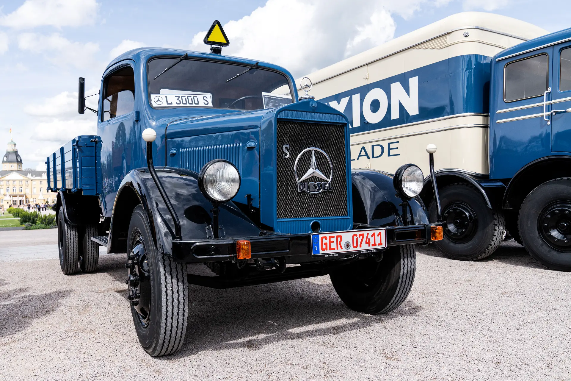 Un camión vintage Mercedes-Benz L 3000 S azul, que recuerda una época pasada, se yergue orgulloso al aire libre, con un edificio de museo al fondo, encarnando el encanto de un borrador automático viviente.