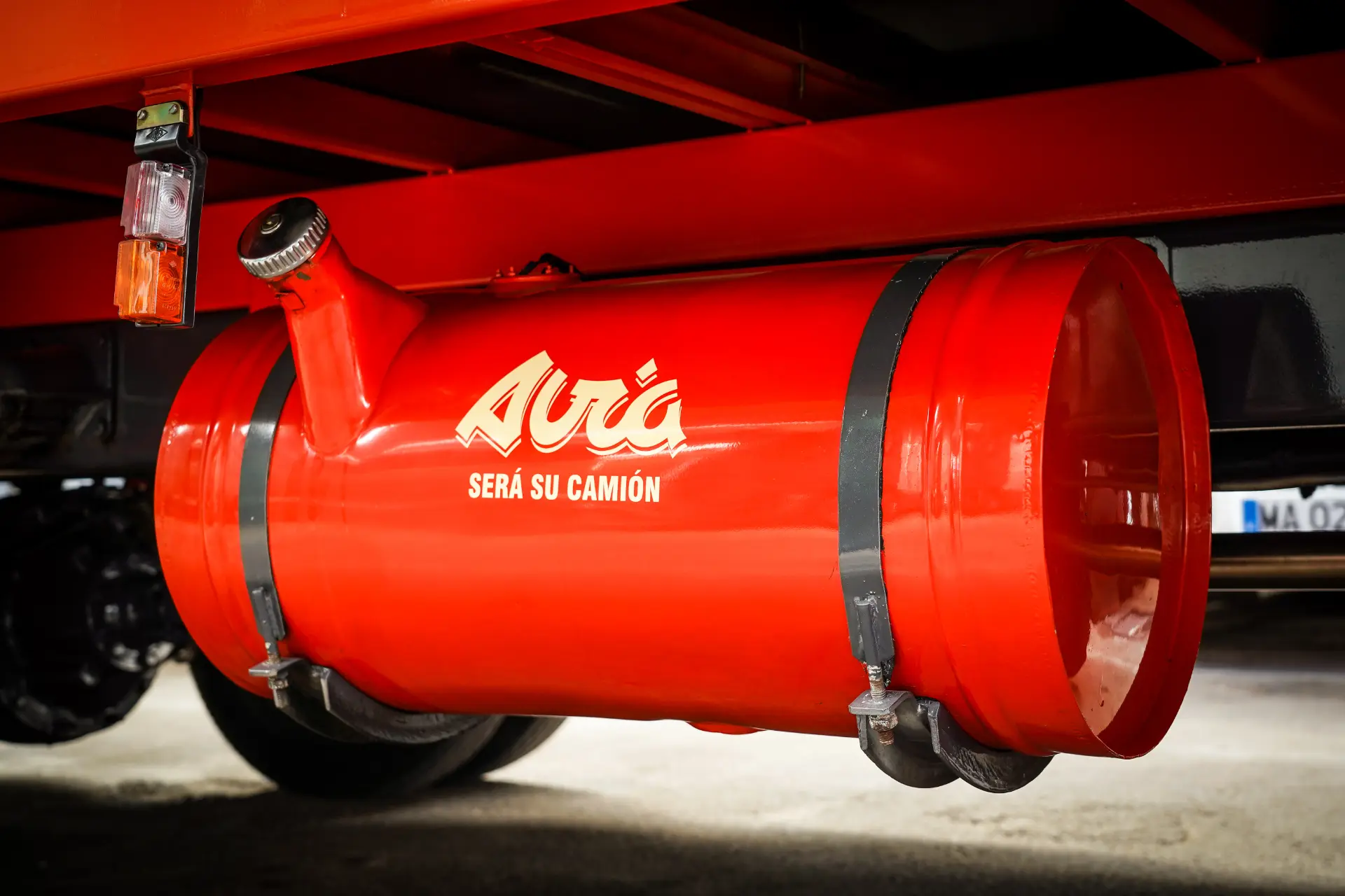 Un tanque de combustible rojo está adherido al chasis de un camión, marcado "Avia Será Su Camión", con un neumático asomando desde atrás, que recuerda a la meticulosa restauración del Avia 3500 realizada por José Ramón García.