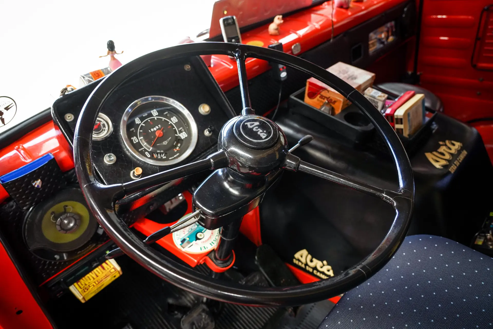Primer plano del salpicadero de un coche clásico con un gran volante y varios gadgets retro, que evoca el encanto del Avia 3500.