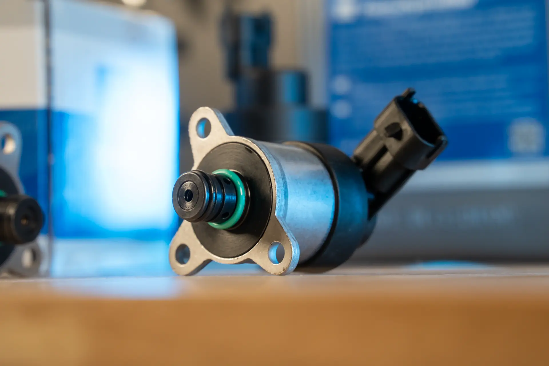 Primer plano de una electroválvula automotriz de metal sobre una mesa con un fondo borroso, que se asemeja a la precisión de un borrador automático.