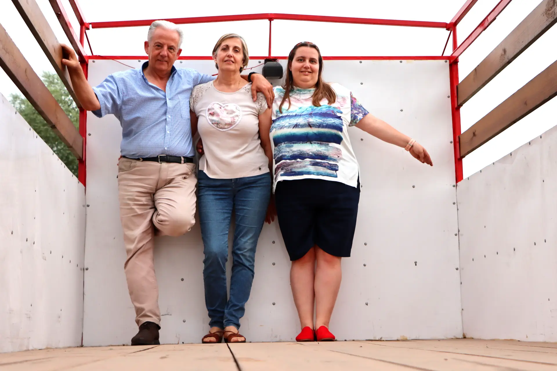 Tres personas están de pie una al lado de la otra en un camión familiar Avia 5000 vacío, sonriendo a la cámara, tal vez capturando un recuerdo con Carlos Torrano.