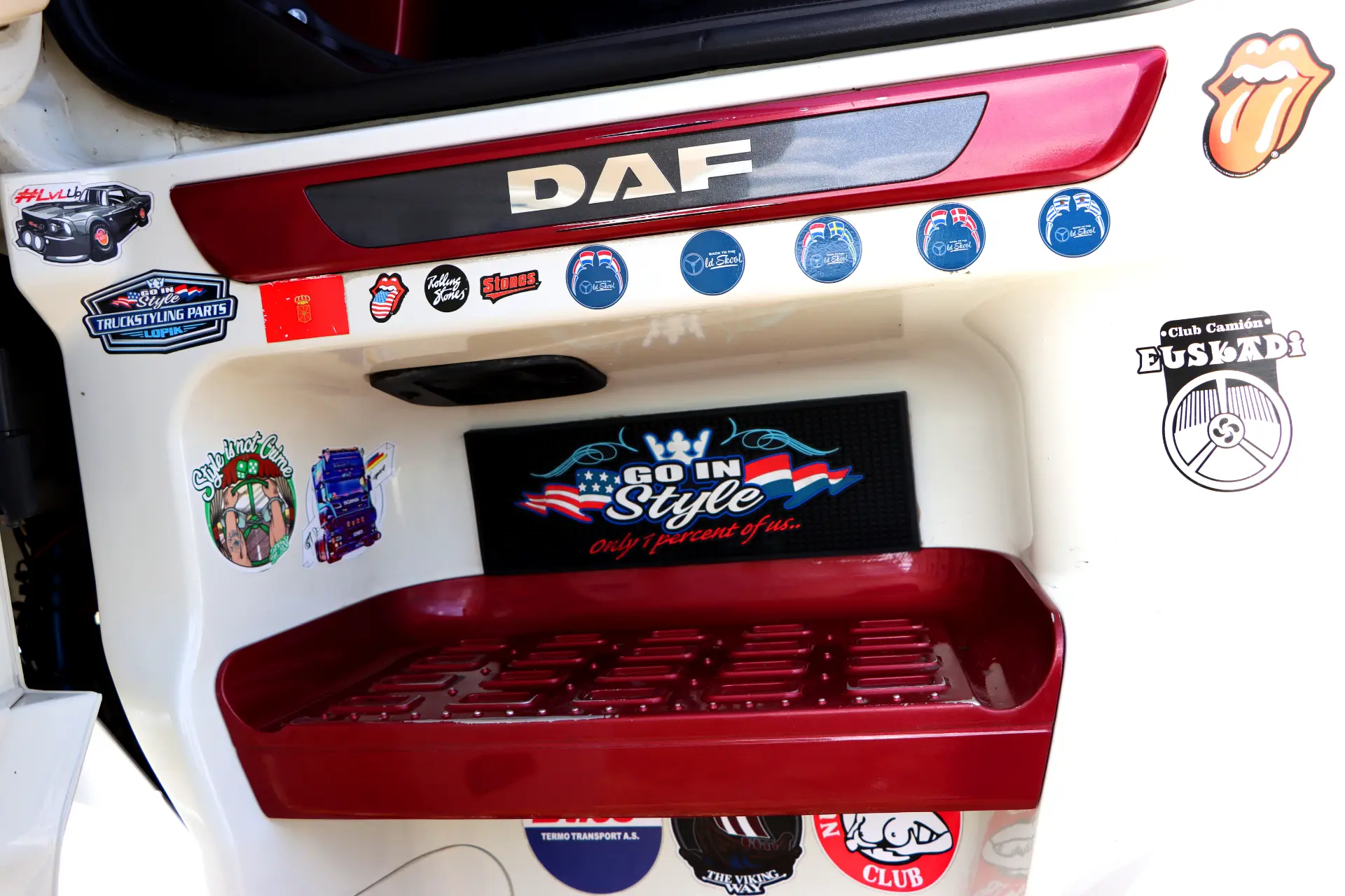 Una puerta de camión blanca decorada con varias pegatinas de colores, incluidos "DAF", "Go In Style" y detalles de estilo holandés, que muestran un aspecto tuneado único de DAF.