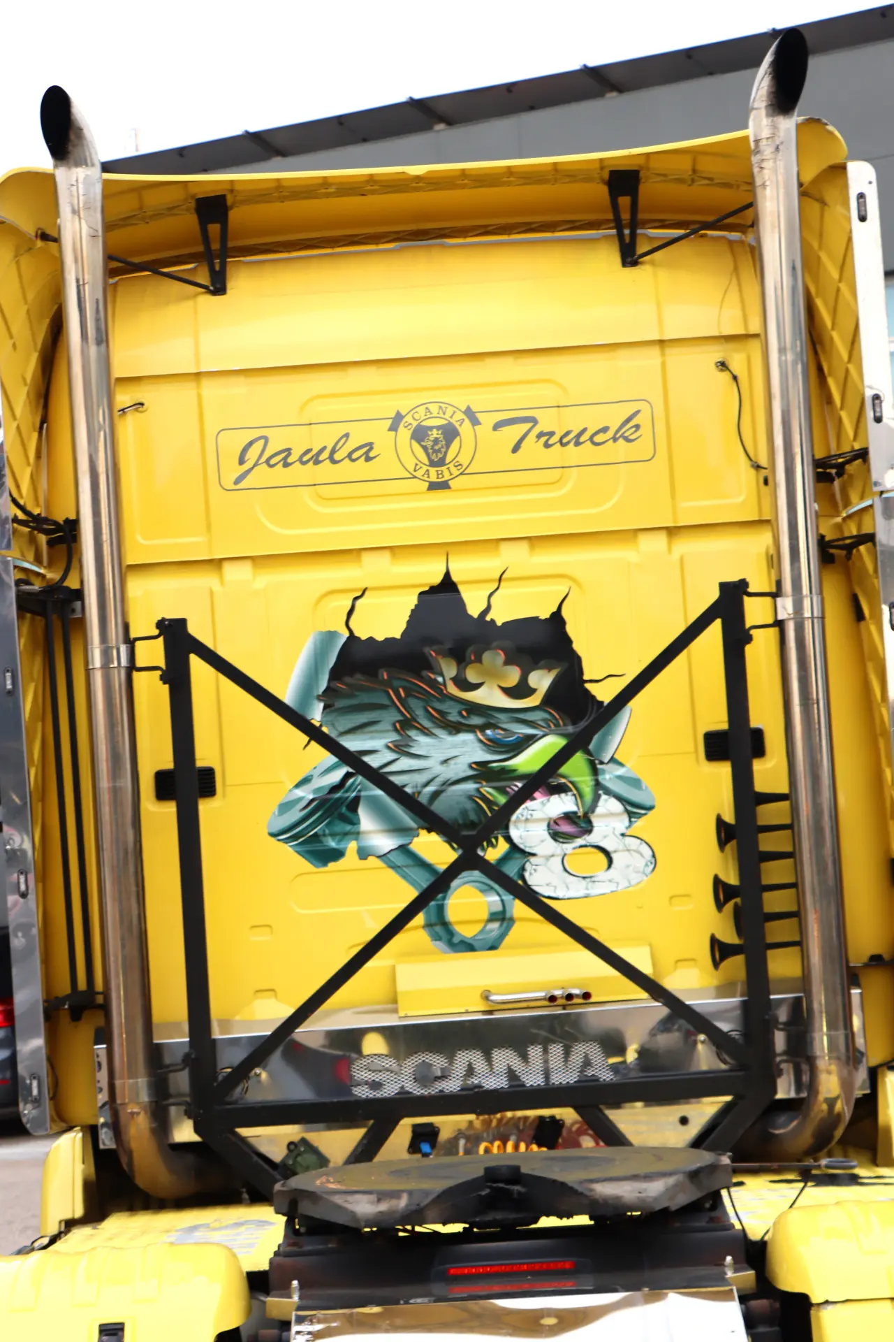 Parte trasera de un camión amarillo con un mural de dragón y el texto "Jaula Truck" encima, visto en carreras camiones España, perfecto para los fanáticos de los camiones americanos tuneados.