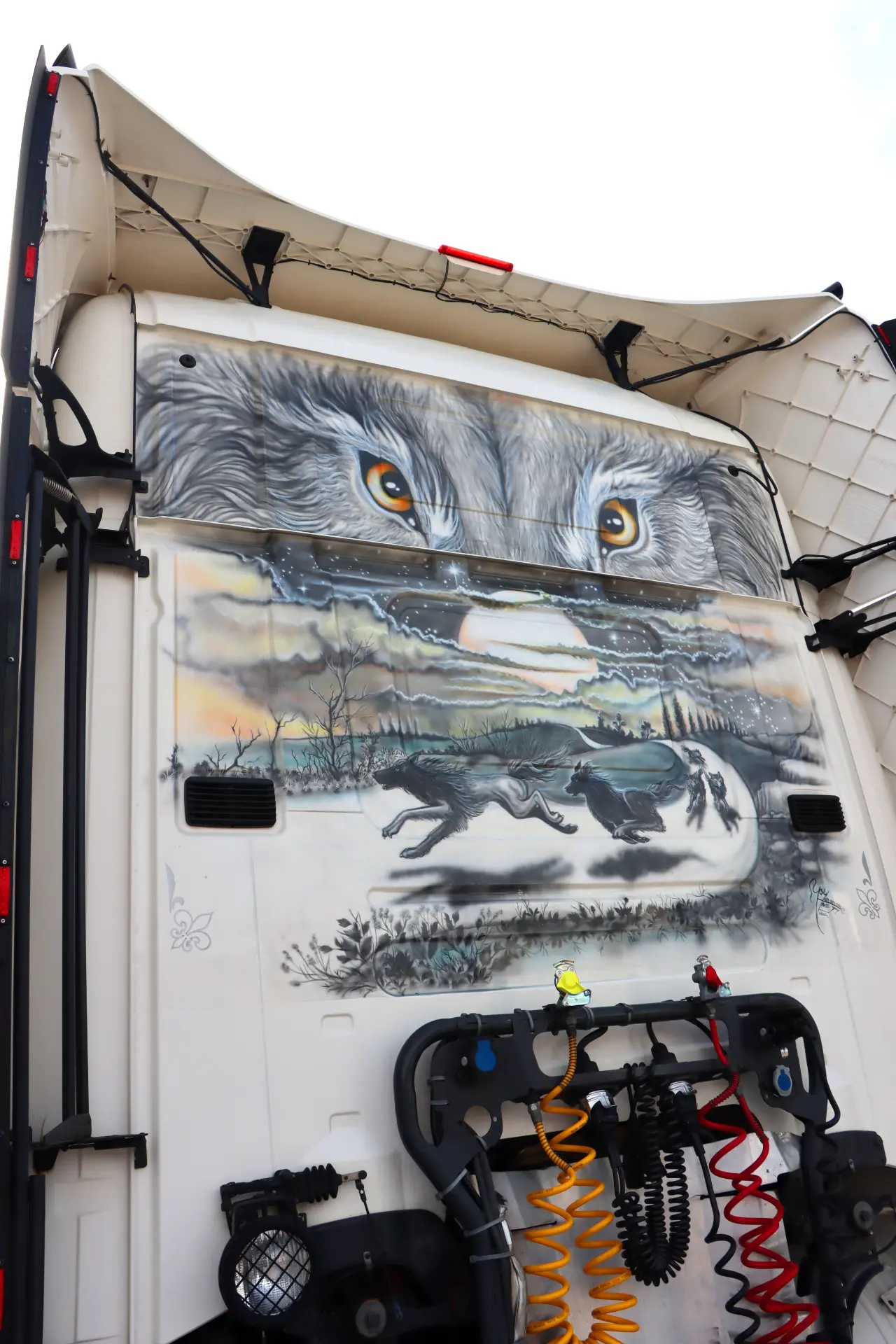 Mural de lobo en la cabina del camión, con ojos de lobo sobre un paisaje con lobos corriendo y una puesta de sol: un ejemplo épico de camiones americanos tuneados perfecto para las carreras de camiones España o el Valencia Nascar Fest 2025.