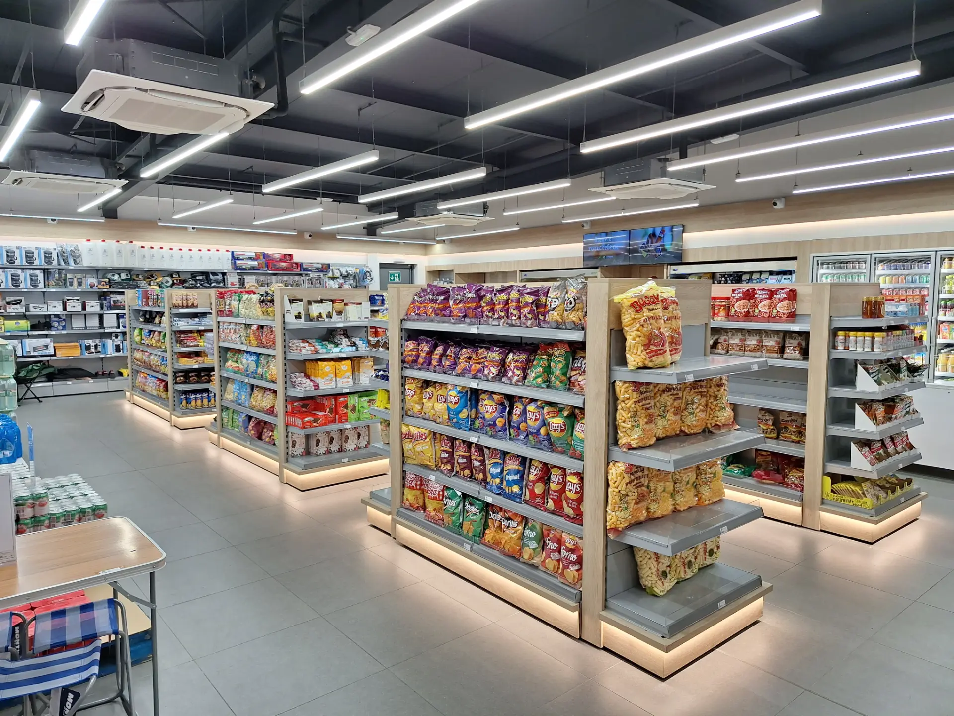 Una tienda de conveniencia bien iluminada con estantes perfectamente organizados de bocadillos y comestibles, que ofrece un servicio de borrador automático perfecto para pagos rápidos y sin complicaciones.