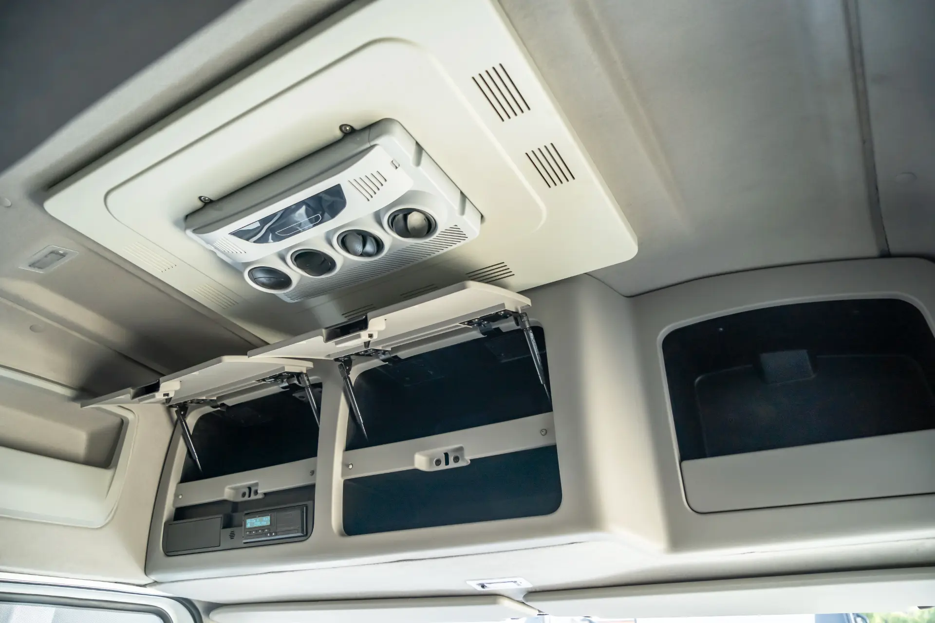 Compartimientos superiores abiertos y unidad de aire acondicionado de techo dentro de un vehículo, probablemente una cabina de camión, resaltando características que complementan el motor Ecotorq y las ventajas de cambio de 16 velocidades para una mayor comodidad del conductor.