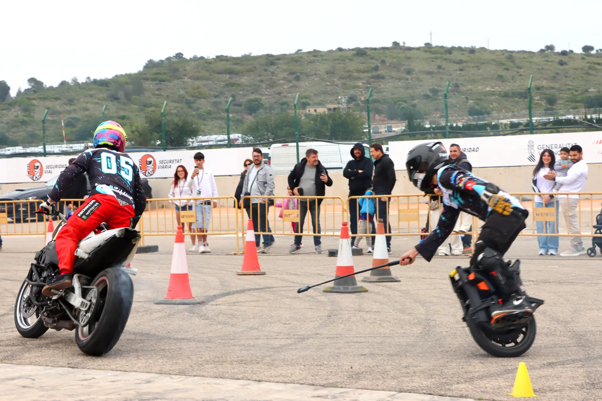 Dos motociclistas maniobran alrededor de conos mientras una multitud observa detrás de una barrera en un evento al aire libre durante el Valencia Nascar Fest 2025.