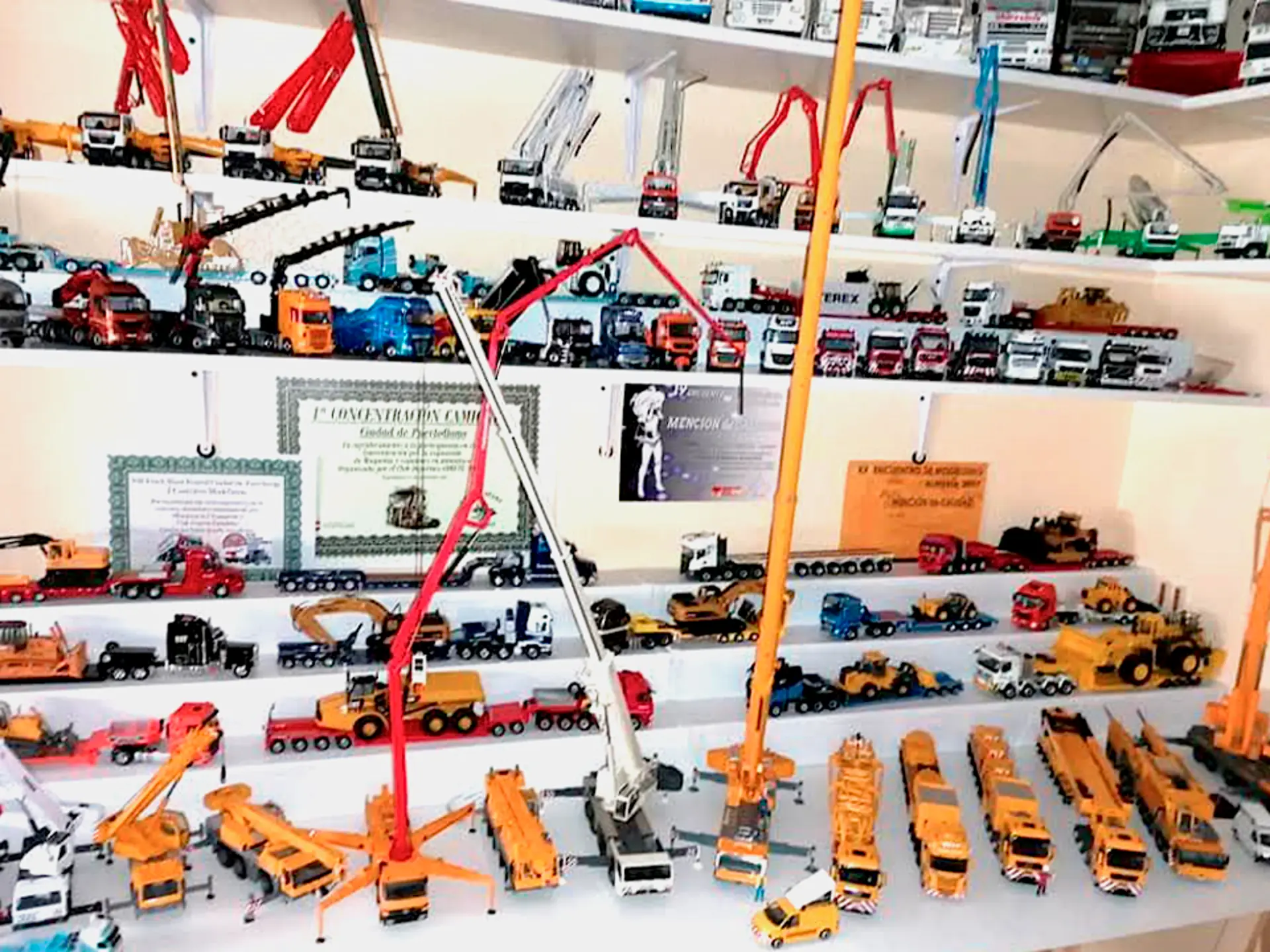 Vehículos y camiones de construcción de juguete exhibidos en estantes blancos, organizados por tipo y color, crean un borrador automático de orden lúdico y diseño vibrante.