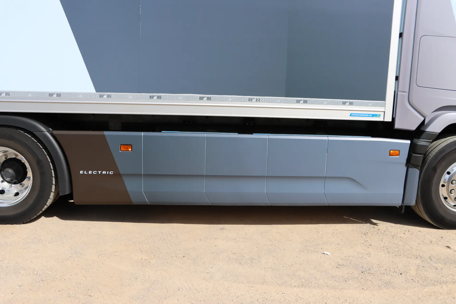 Primer plano del lateral de un Scania 40R eléctrico estacionado sobre una superficie arenosa, resaltando la rueda y el panel inferior durante una prueba Scania 40R.
