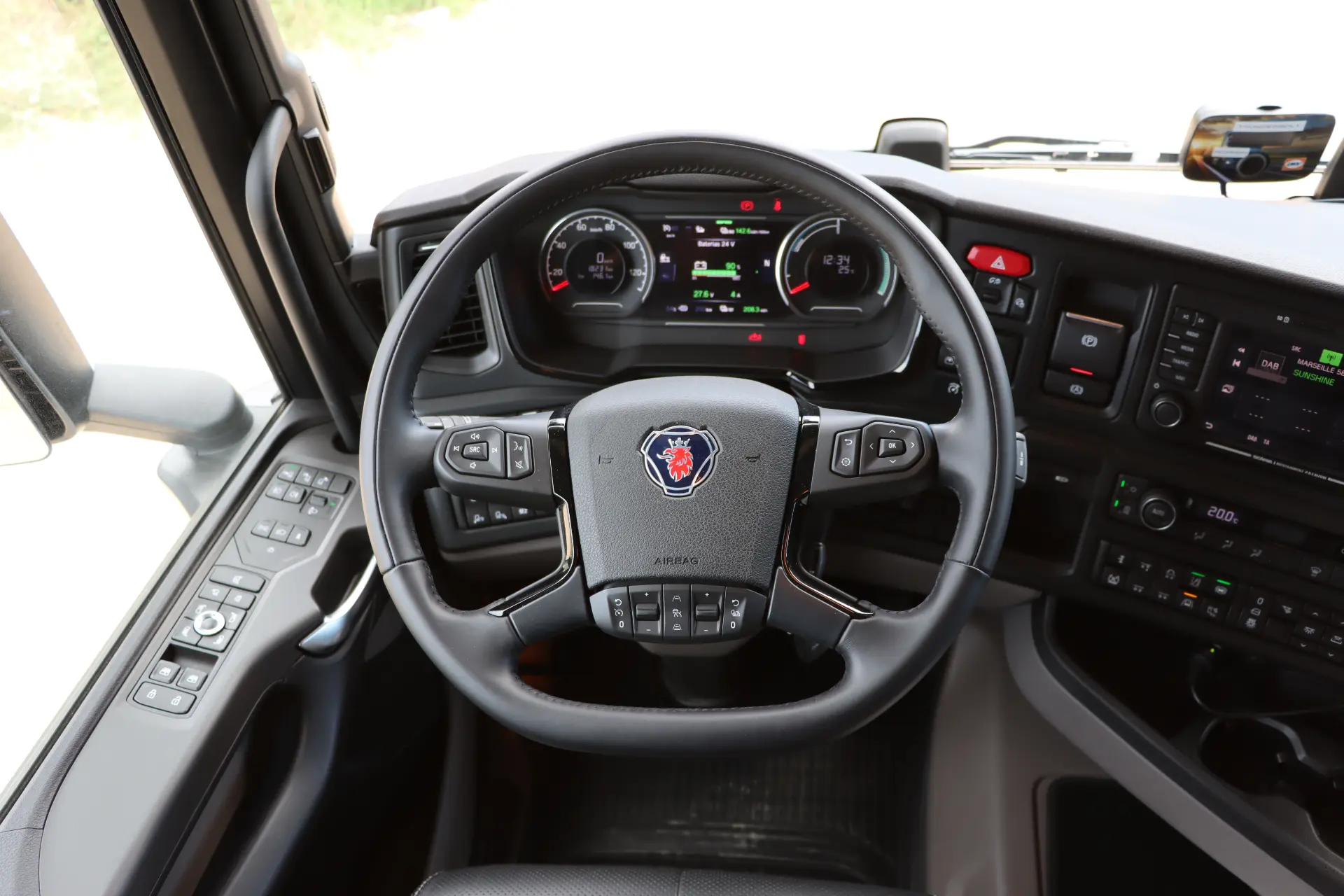 Primer plano de un volante eléctrico Scania 40R y un tablero con controles digitales y analógicos, destacando características durante una prueba ciudad carretera—vale la pena descubrir su innovación.