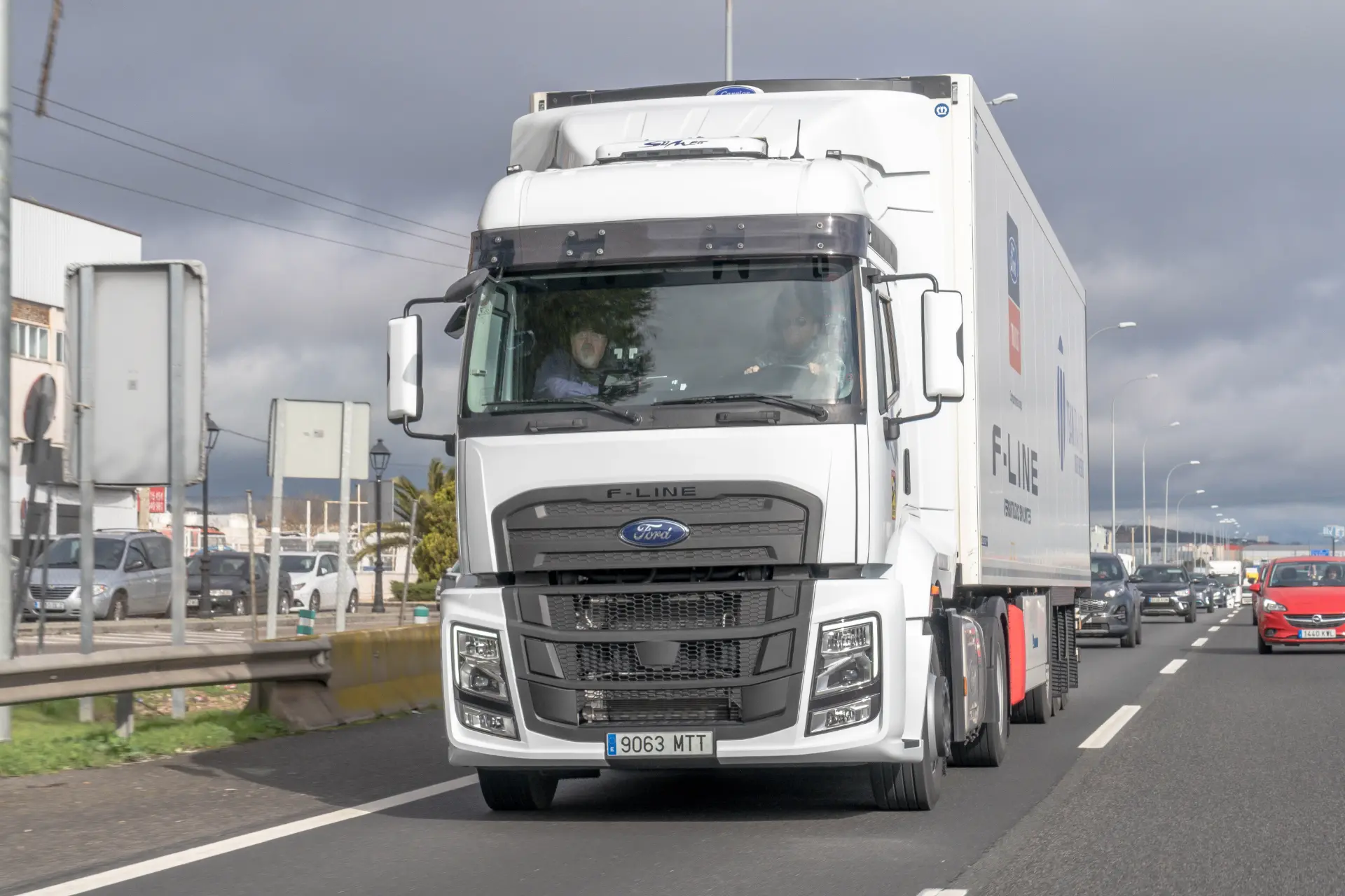 Un camión semirremolque Ford Trucks F-Line 1845T blanco circula por una carretera bajo un cielo nublado, ideal para mostrar las ventajas del cambio de 16 velocidades en cada viaje.