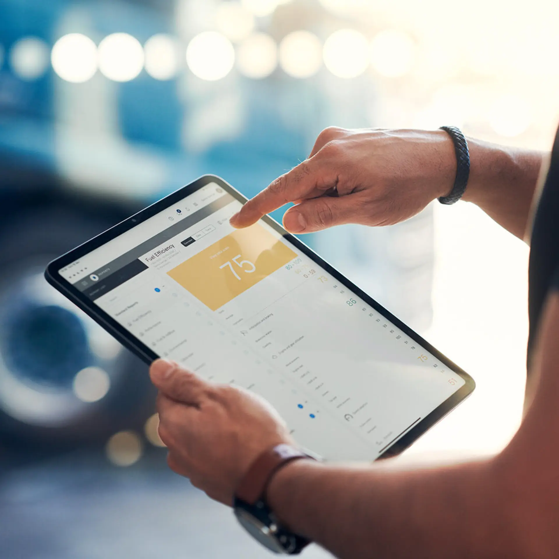 Primer plano de manos utilizando una tableta con gráficos y datos del sistema Volvo Connect, ideal para la gestión flotas camiones Volvo y monitorización del tacógrafo digital.