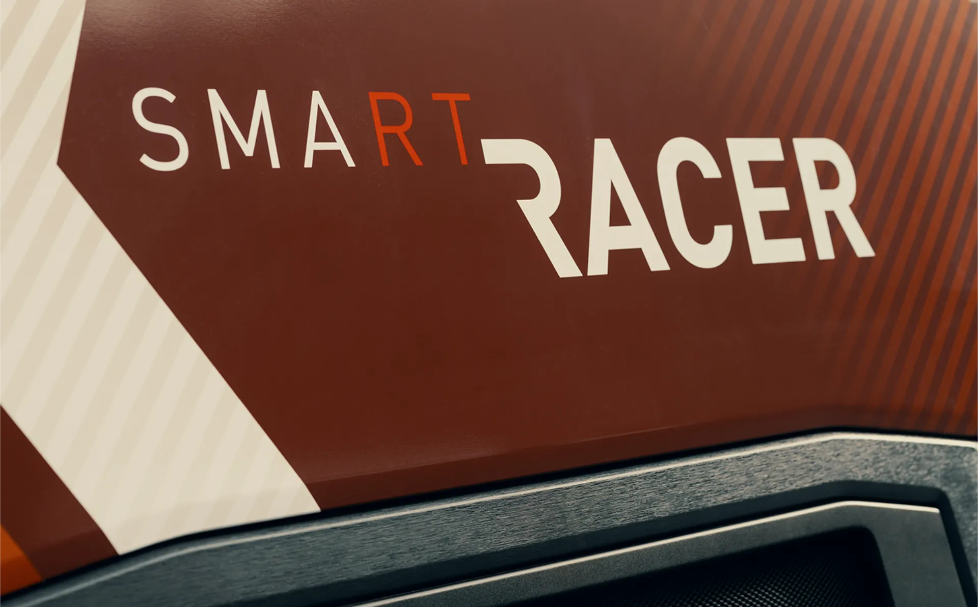 Primer plano de un cartel que dice "SMART RACER" en una fuente moderna y en negrita sobre un fondo marrón, similar al estilo limpio de un borrador automático.